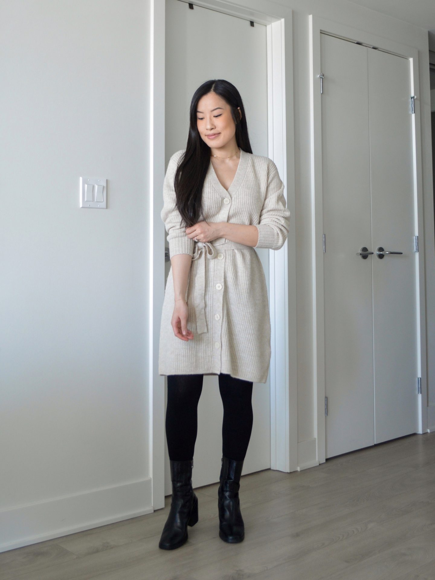 Sharon of Her Simple Sole is wearing the Frank and Oak The Recycled Wool Cardigan Dress with the fabric belt tied to the front, with tights and black ankle boots.