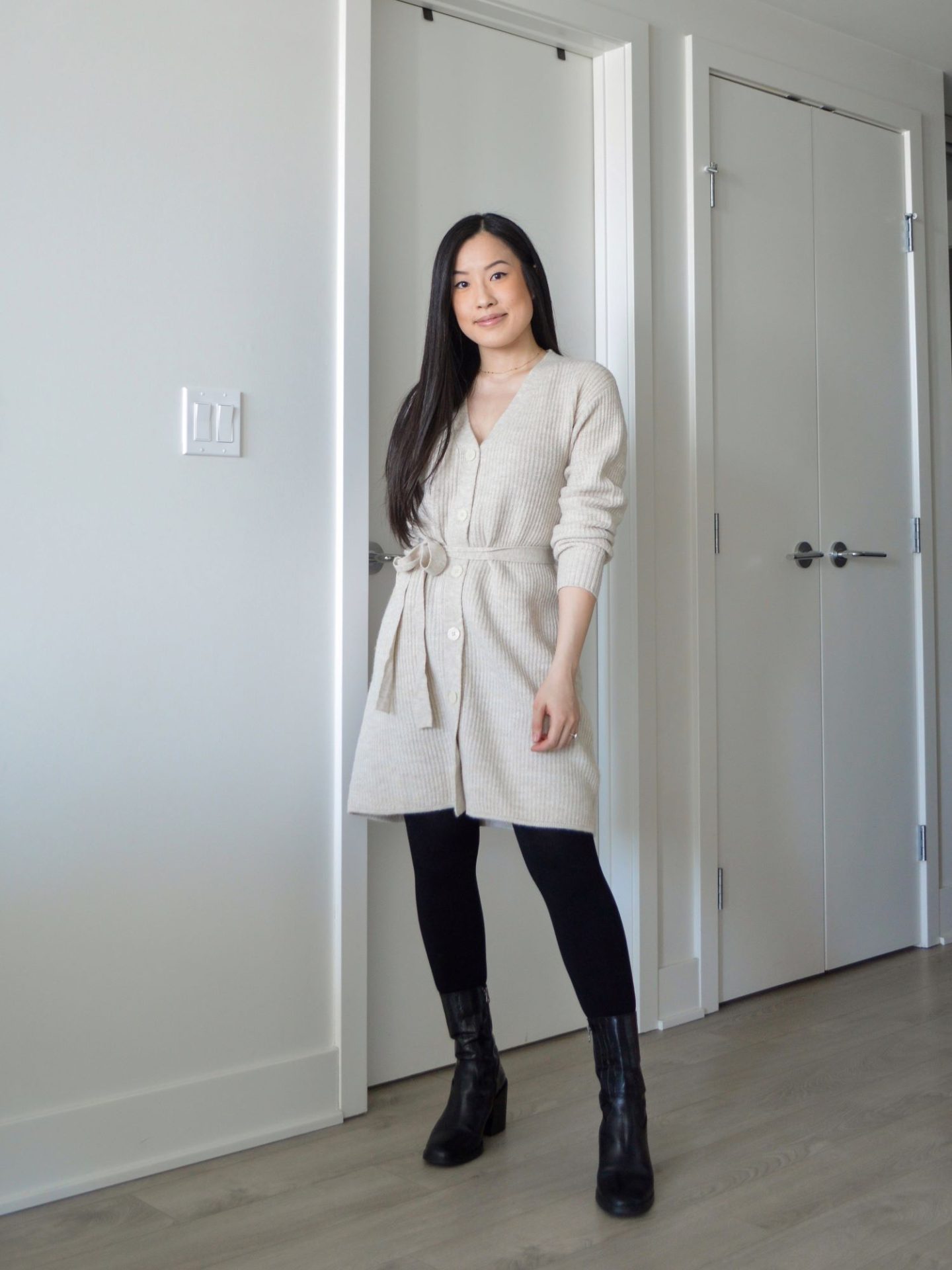 Sharon of Her Simple Sole is wearing the Frank and Oak The Recycled Wool Cardigan Dress with the fabric belt tied to the front, with tights and black ankle boots.