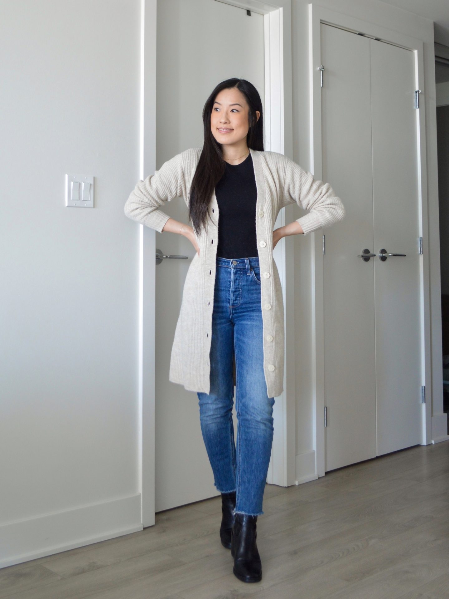 Sharon of Her Simple Sole is wearing the Frank and Oak The Recycled Wool Cardigan Dress opened with a black long sleeve tshirt, blue slim jeans and black ankle boots.