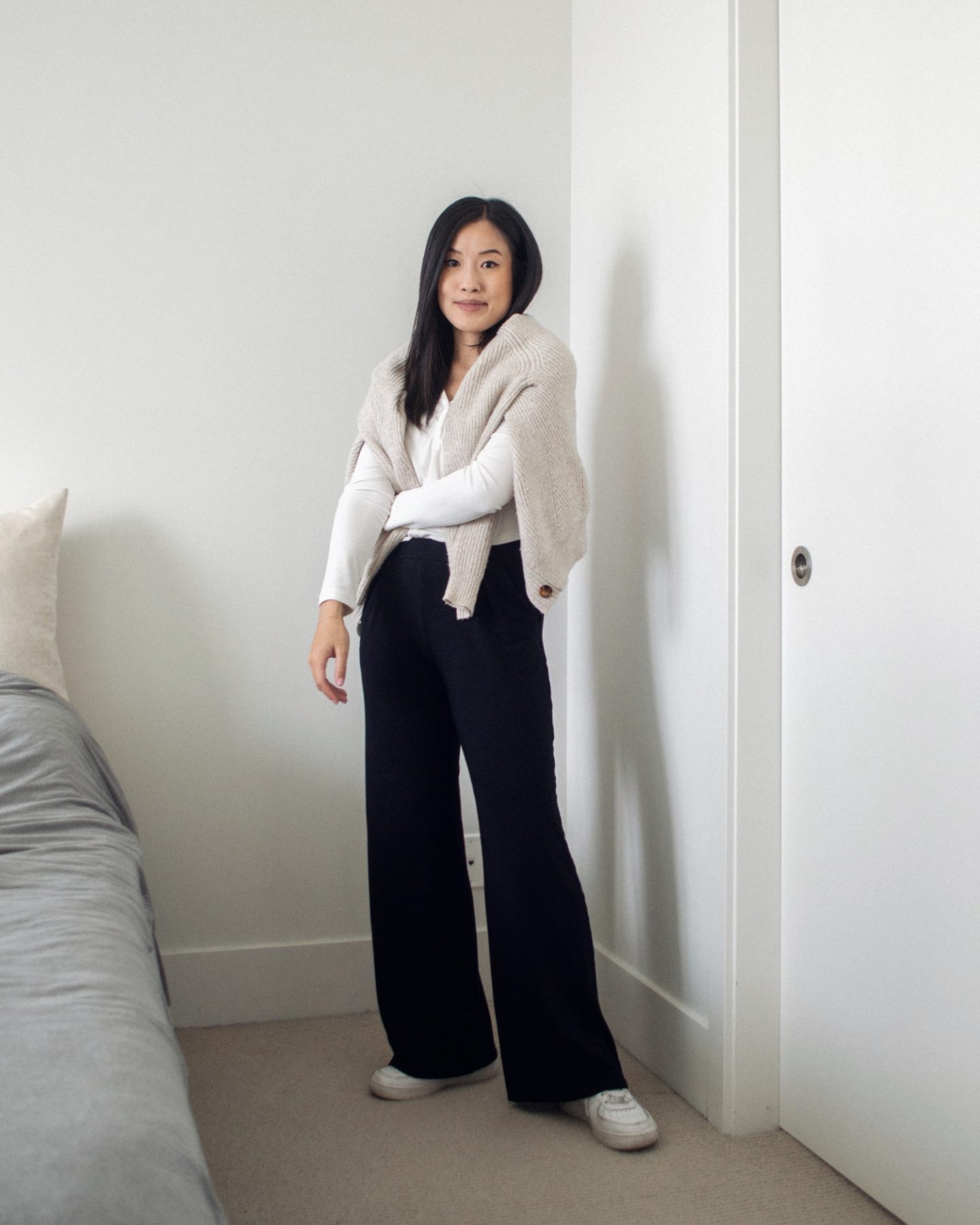 Outfit details - knit cardigan over shoulders, white henley top, black wide leg pants, white sneakers, cozy outfit, work from home outfit