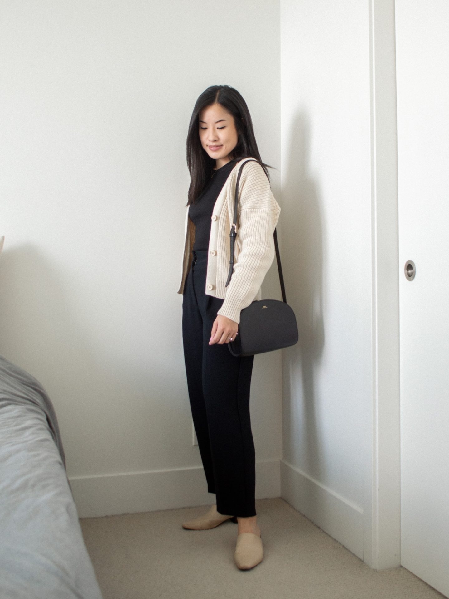 Outfit details: Tradlands Shelter Cardigan in Birch, Kotn High Neck Tank, Wilfred Trousers from Aritzia, Maguire Boutique Navio Mules, A.P.C. Black Demi-Lune Bag, monochrome black outfit base, fall transition outfit, layering outfit for fall, cozy cardigan outfit