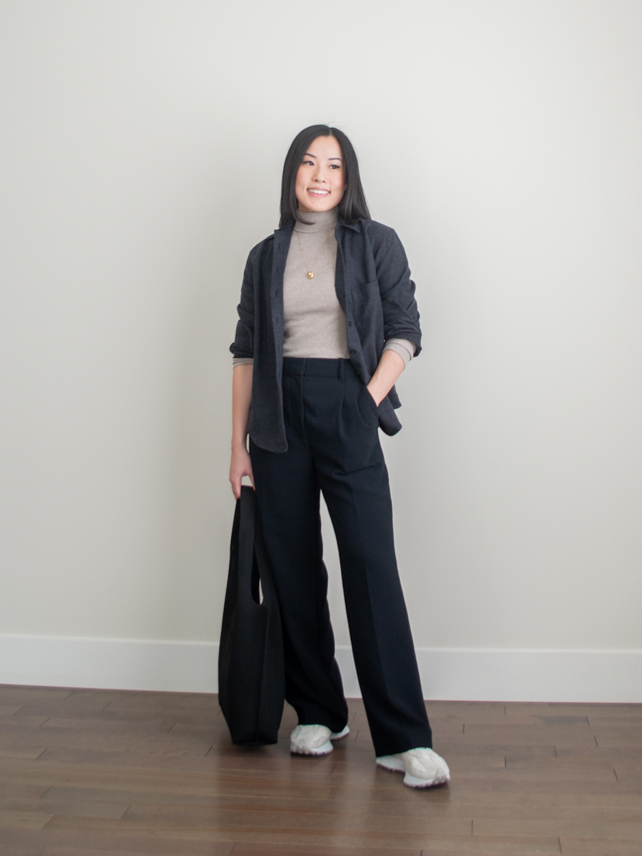 Her Simple Sole outfit photo featuring a brushed cotton heather black button up shirt, fitted turtleneck tee, black wide leg pants, New Balance sneakers, black tote bag