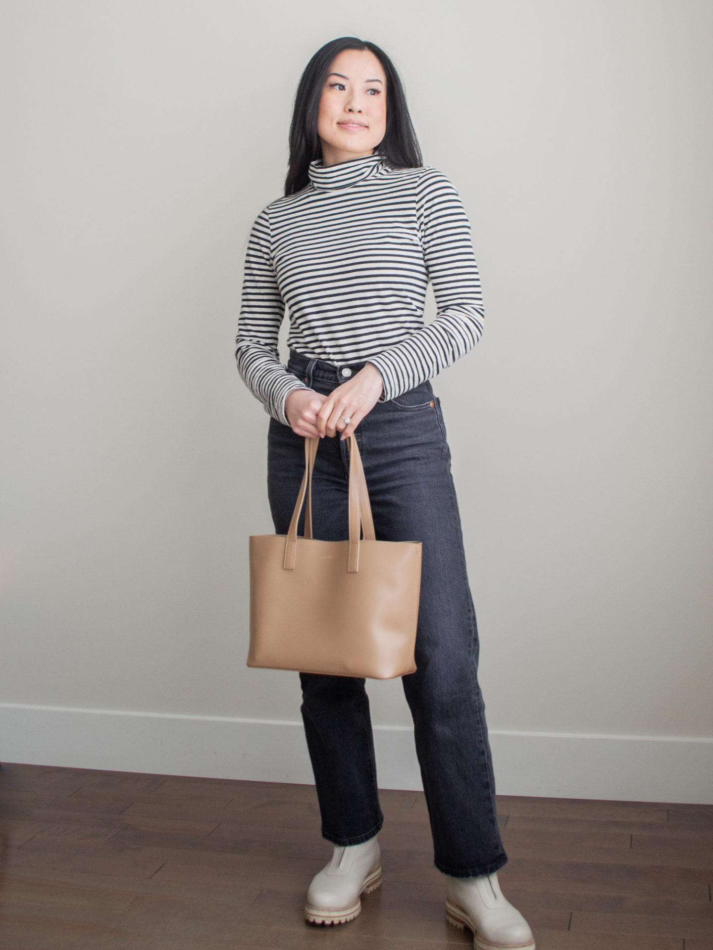 Casual outfit idea: small caramel tote bag, strip turtleneck top, grey straight leg jean, cream chunky boots