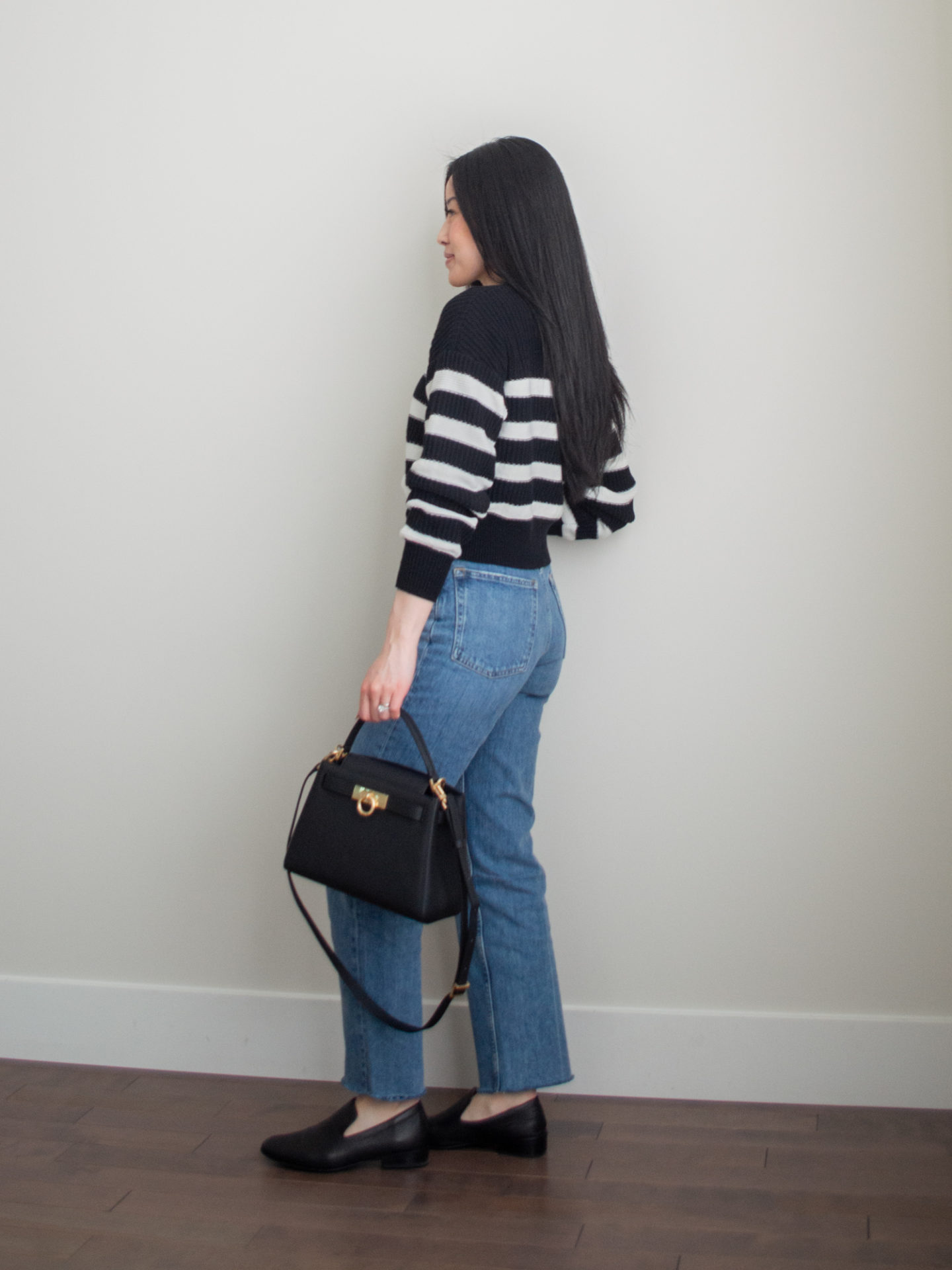 Smart casual outfit idea: black and white stripe cardigan, blue jeans, black classic loafers, square crossbody bag