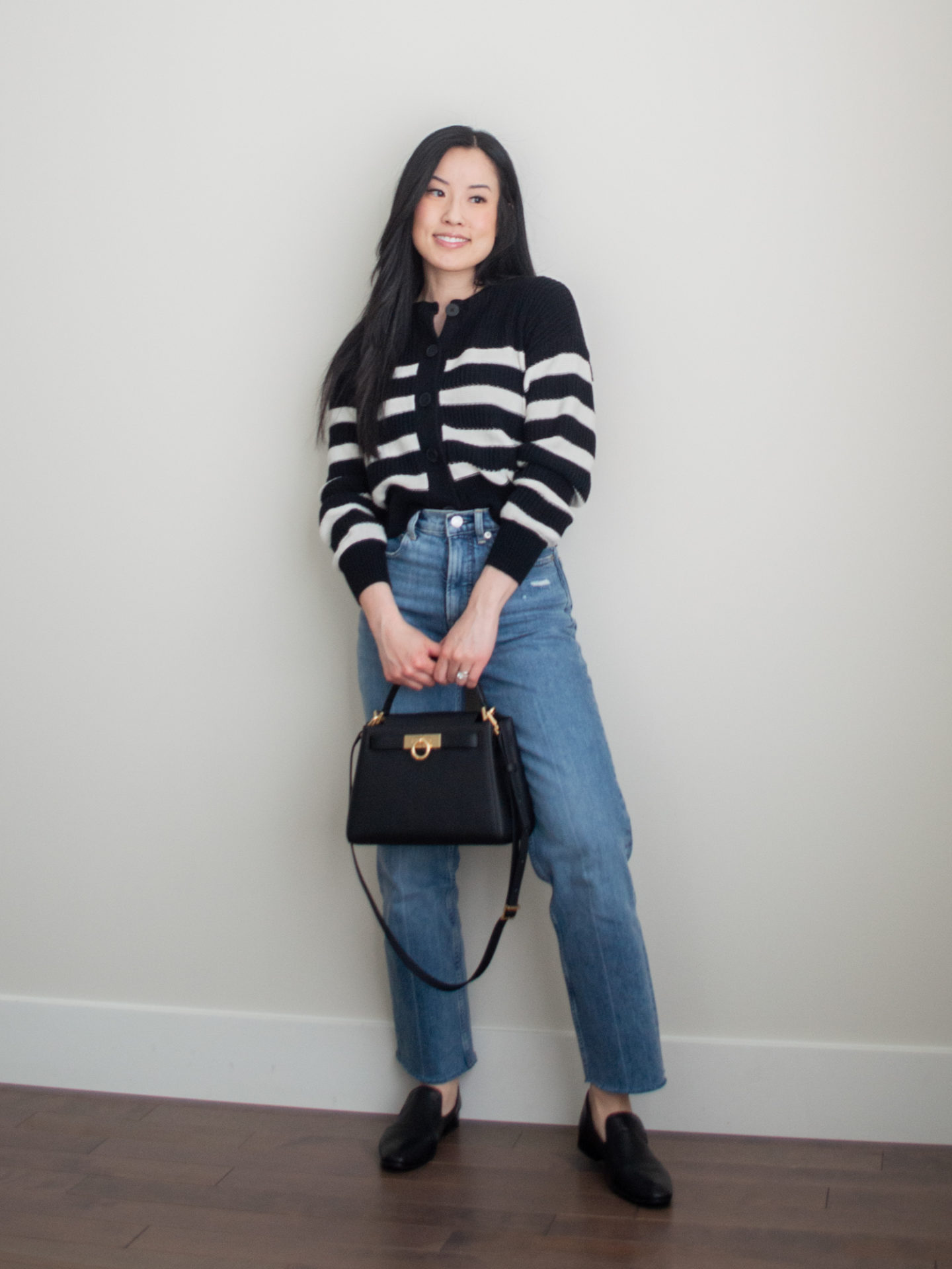 Smart casual outfit idea: black and white stripe cardigan, blue straight leg jeans, black classic loafers, square crossbody bag