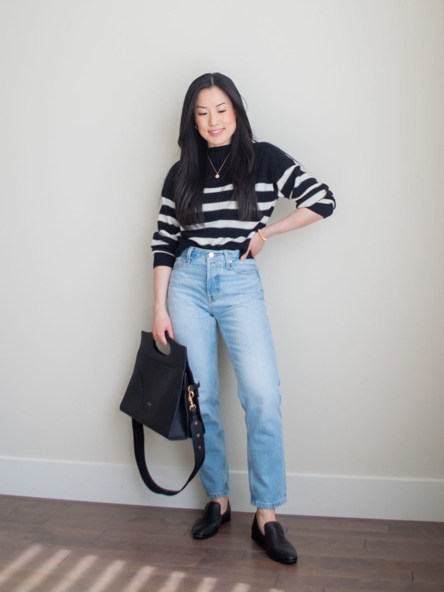 A casual chic outfit worn by Sharon of Her Simple Sole, featuring a black and white stripe sweater, blue straight leg jeans, gold dainty jewelry, and the Oleada Wavia bag in Champagne | spring outfit idea | minimalist outfit