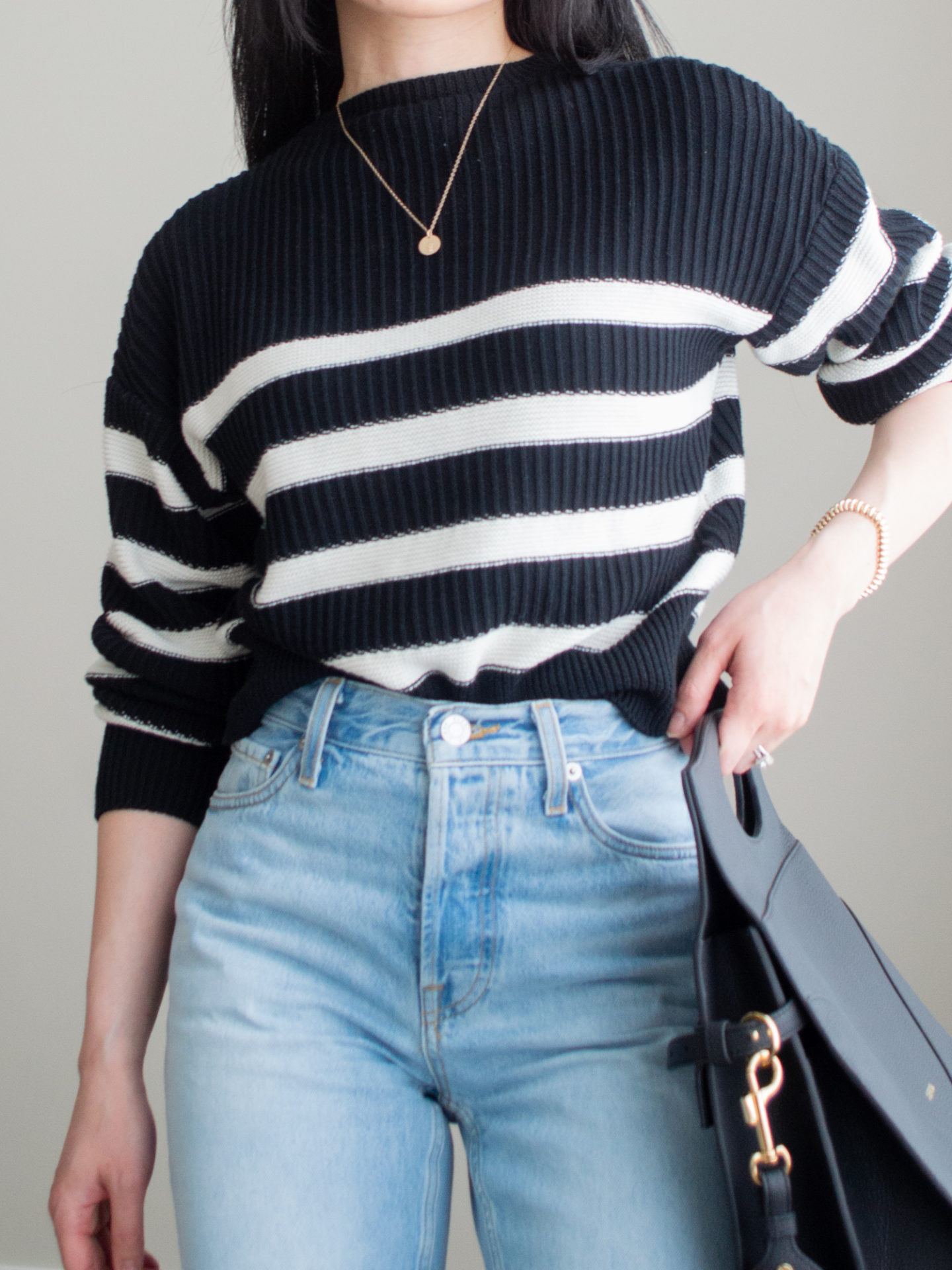 Close up shot of a casual chic outfit worn by Sharon of Her Simple Sole, featuring a black and white stripe sweater, blue straight leg jeans, gold dainty jewelry, and the Oleada Wavia bag in Champagne | spring outfit idea | minimalist outfit