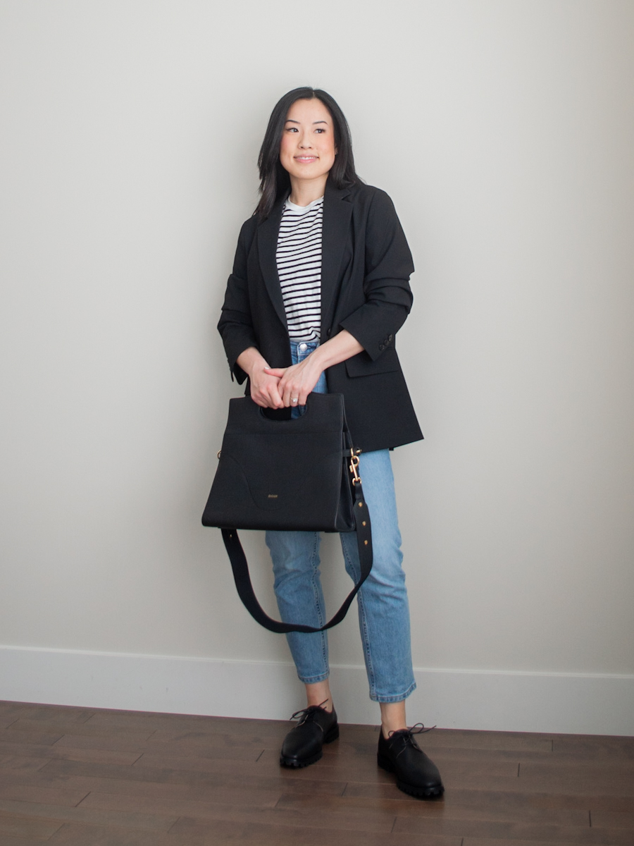 Intentional Life & Style Content Creator Sharon of Her Simple Sole is wearing a smart casual spring outfit featuring a black relaxed blazer, a stripe black and white t-shirt, blue straight leg jeans, black oxford shoes, and the Oleada Captain Briefcase | simple styling tips | smart casual outfit | the three color rule | the third piece rule | fashion style tips | casual blazer outfit