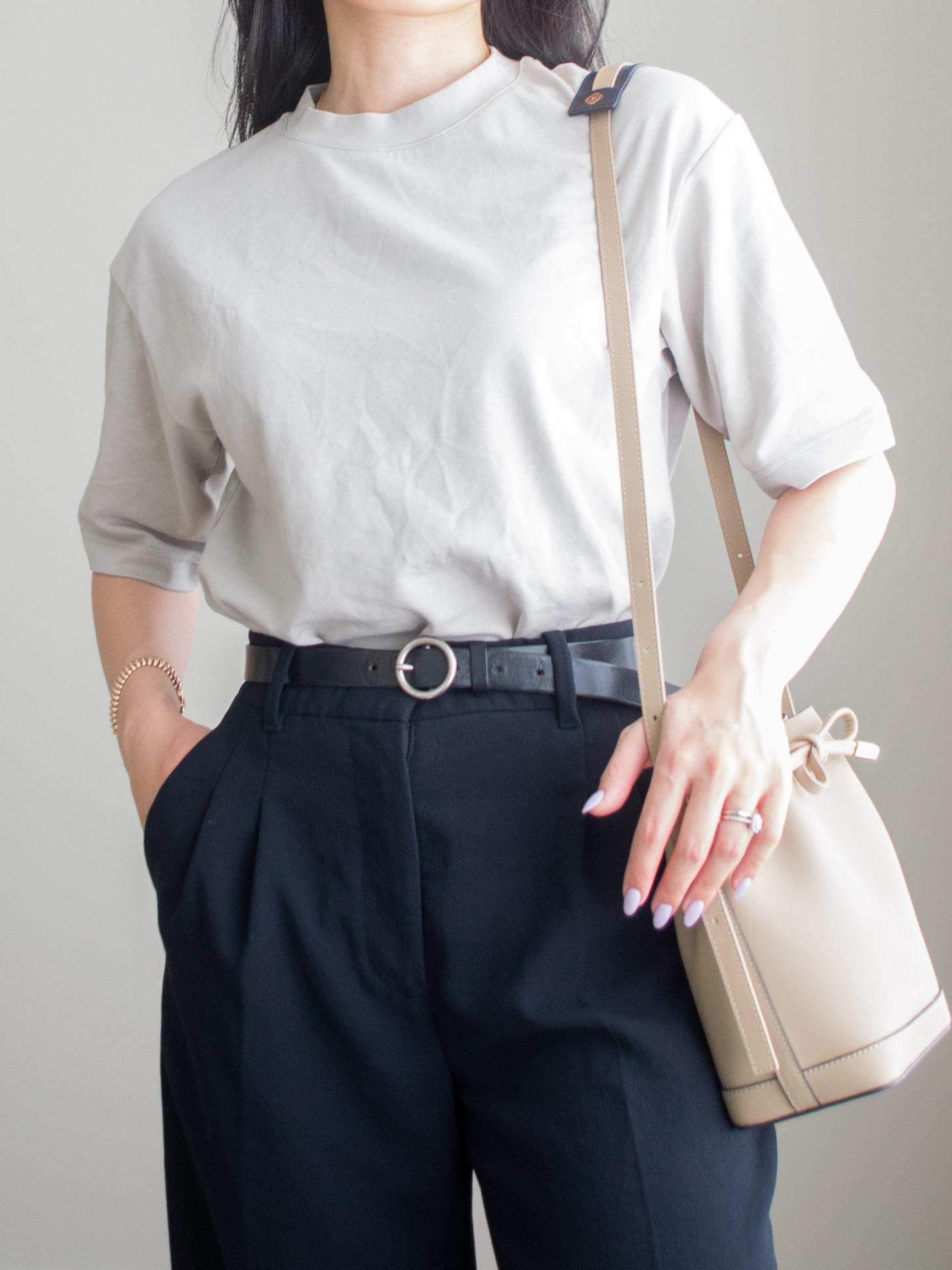 Close-up detailed outfit shot of Sharon of Her Simple Sole wearing an oversized t-shirt and wide leg pats outfit with a black belt and bucket bag | minimalist outfit ideas | smart casual outfit