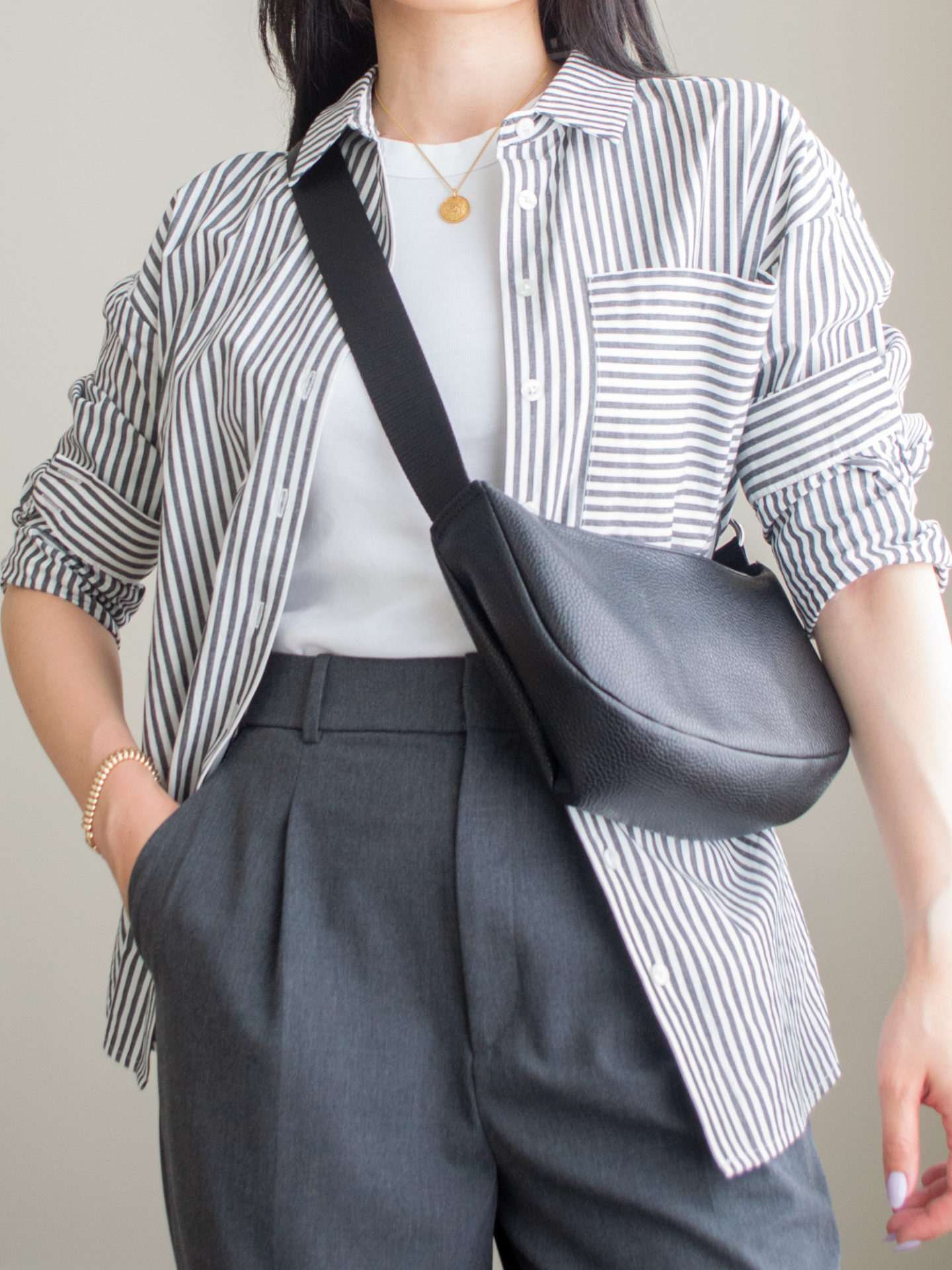 Close-up detailed outfit shot of Sharon of Her Simple Sole wearing a white tank top and grey wide leg pants with a striped button down shirt and a slouchy crossbody bag | minimalist outfit ideas | smart casual outfit