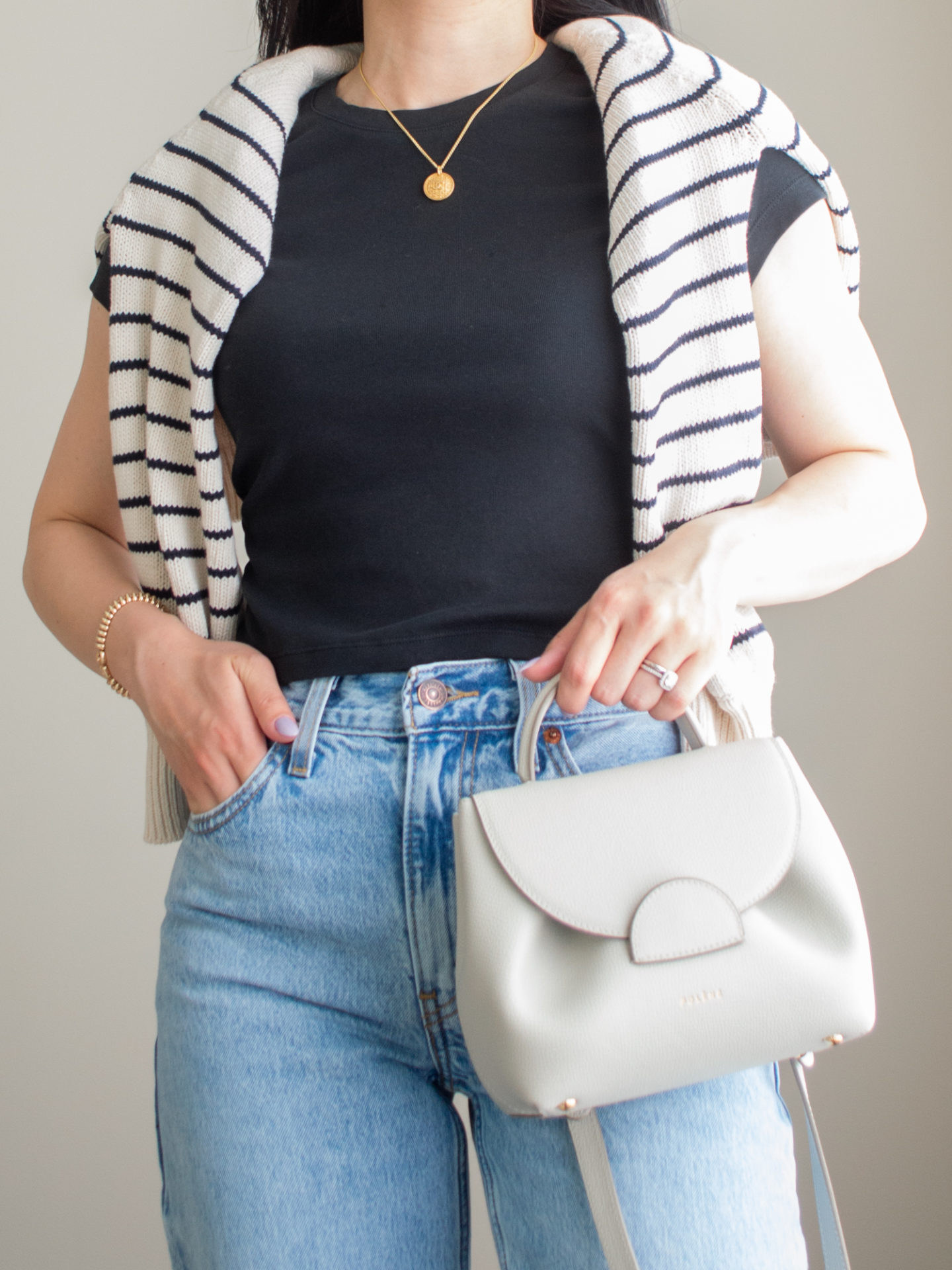 Close-up detailed outfit shot of Sharon of Her Simple Sole wearing a baby tee and slouchy jeans with a striped sweater over the shoulders | minimalist outfit ideas | smart casual outfit