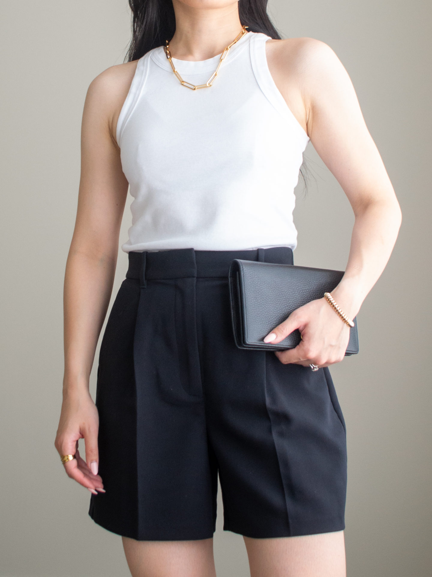 Close-up detailed outfit shot of Sharon of Her Simple Sole wearing a basic white racerback tank top, black tailored shorts, and a statement chain necklace, while holding a Gucci Marmont leather mini chain bag | minimalist outfit ideas | tank top and shorts outfit