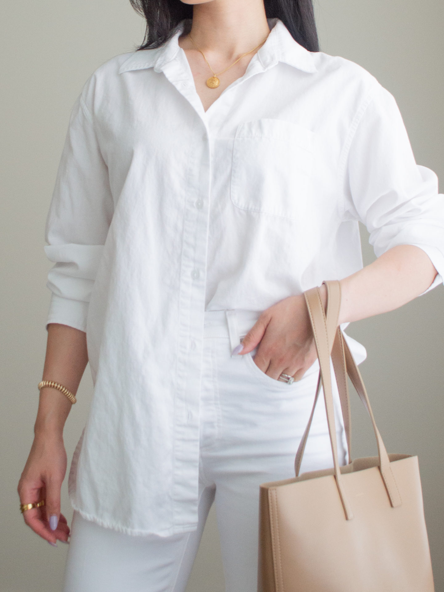 Close-up detailed outfit shot of Sharon of Her Simple Sole wearing a white oversized button up shirt and white straight leg jeans, while holding a caramel coloured mini tote bag | minimalist outfit ideas | smart casual outfit