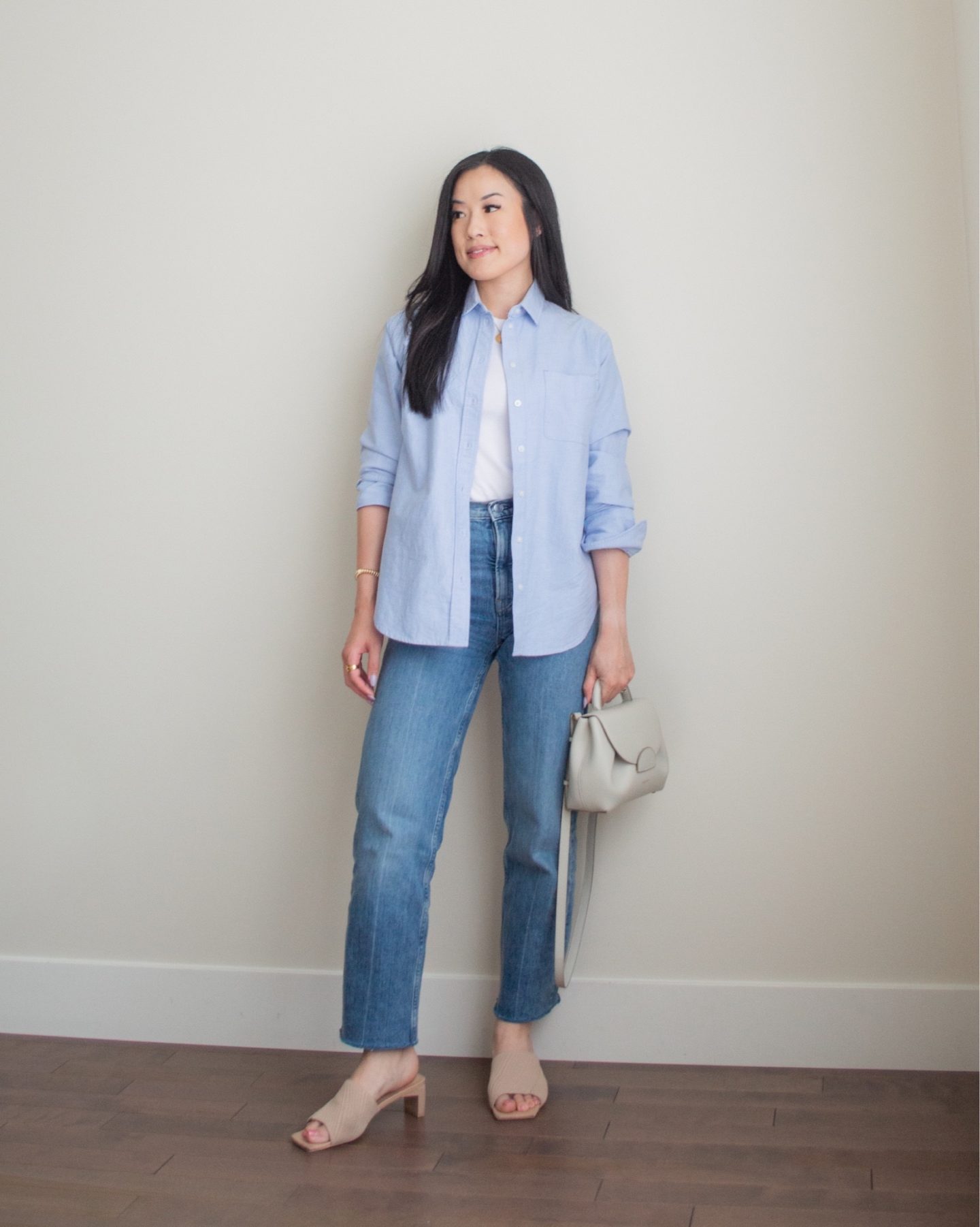 Sharon of Her Simple Sole is wearing an outfit from her June outfit roundup, including a basic cotton tank top, a blue relaxed oxford button up shirt, and blue straight leg jeans, while holding a Polene crossbody bag and wearing neutral open toe mules | minimalist outfit ideas | smart casual outfit | tshirt and wide leg pants outfit