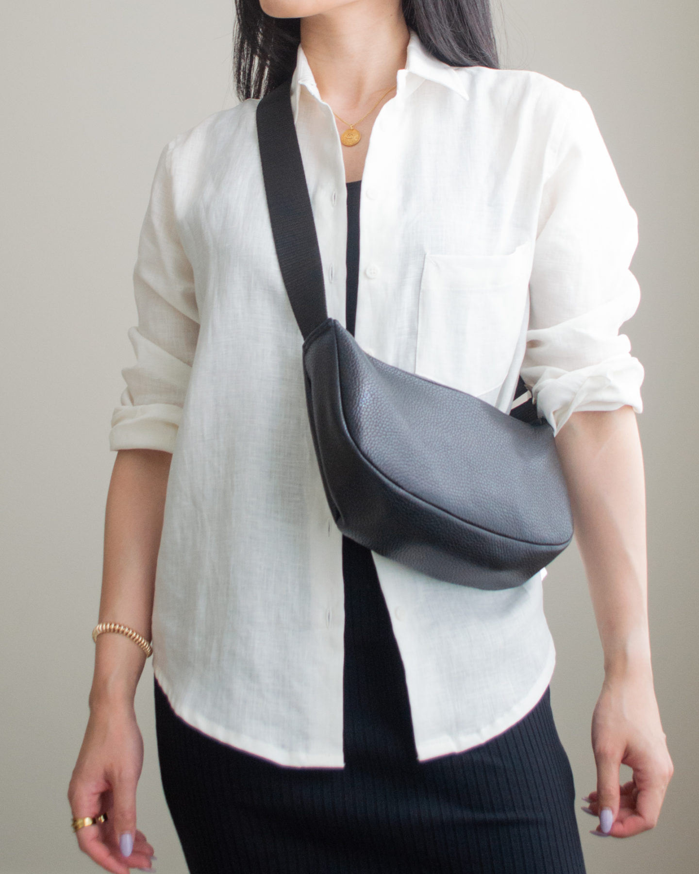 Close-up detailed outfit shot of Sharon of Her Simple Sole wearing a black ribbed midi dress and a long sleeve linen button up shirt, while holding a black slouchy bag | minimalist outfit ideas | smart casual outfit