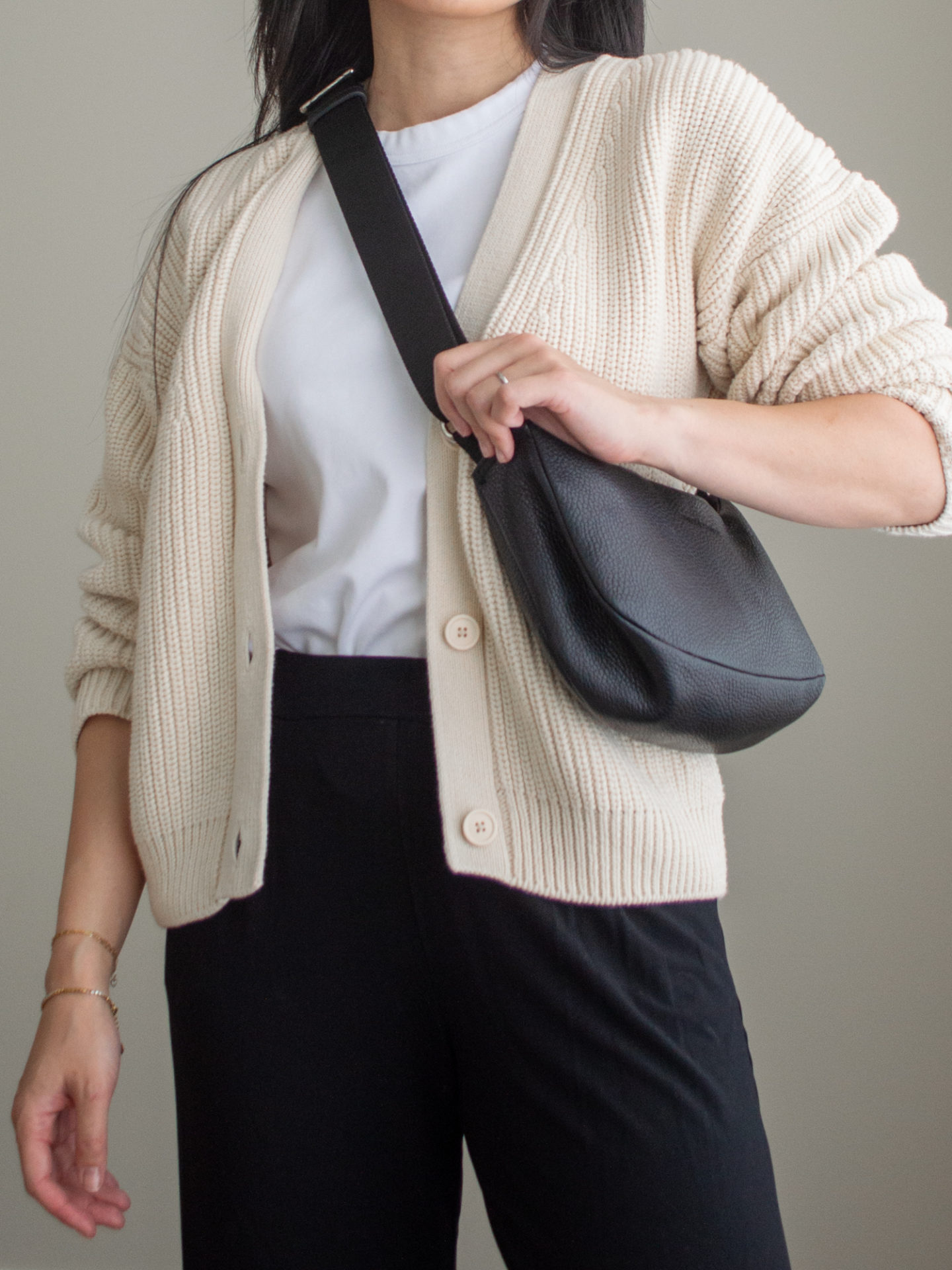 Close-up detailed outfit shot of Sharon of Her Simple Sole wearing a simple white T-shirt, cream cotton cardigan, black wide-leg pants, and a black slouchy bag | minimalist outfits | fall outfit ideas