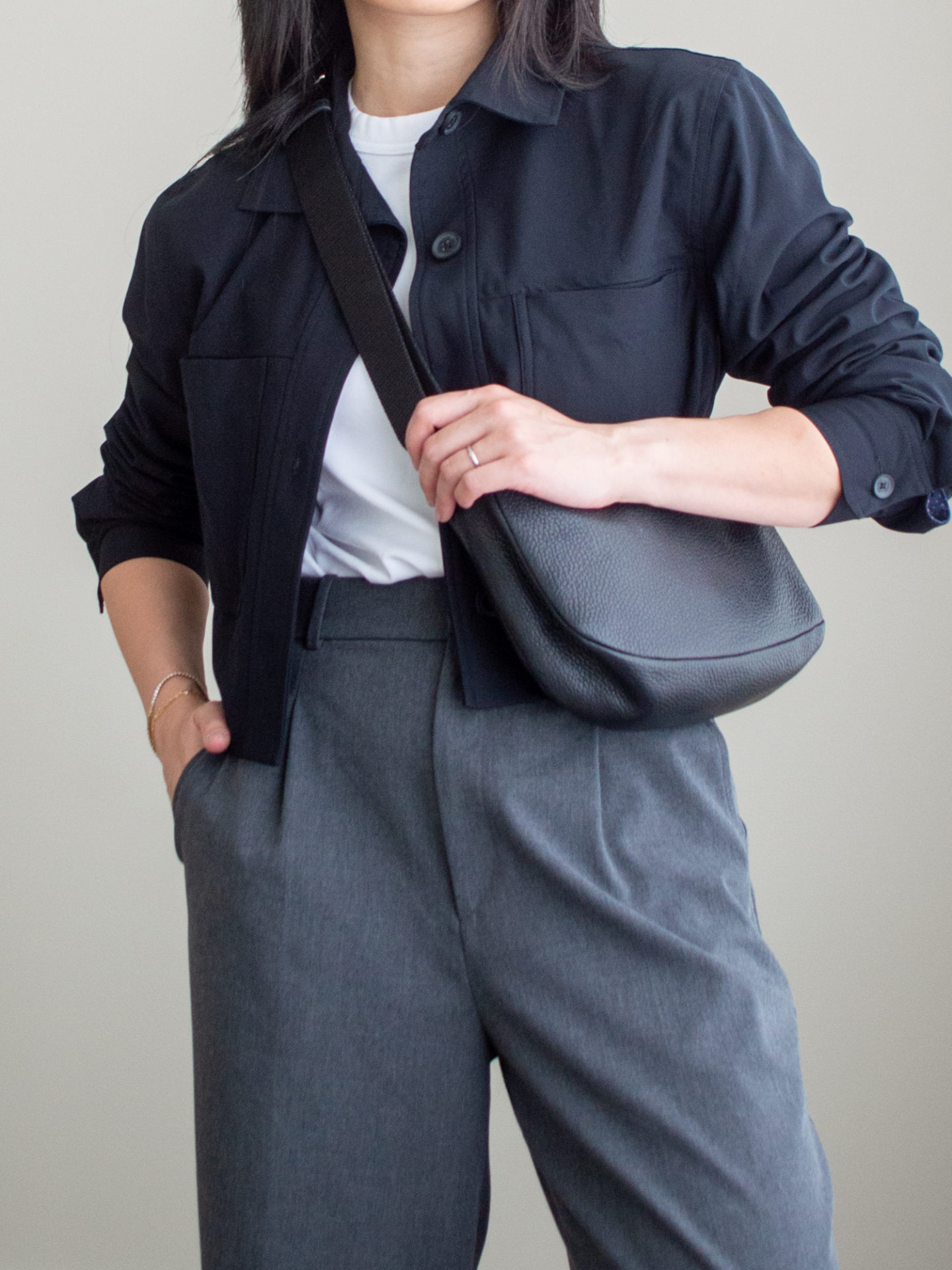 Close-up detailed outfit shot of Sharon of Her Simple Sole waring a simple white T-shirt, a black cropped jacket, a pair of grey wide-leg pants, and a black slouchy bag | minimalist outfits | fall outfit ideas