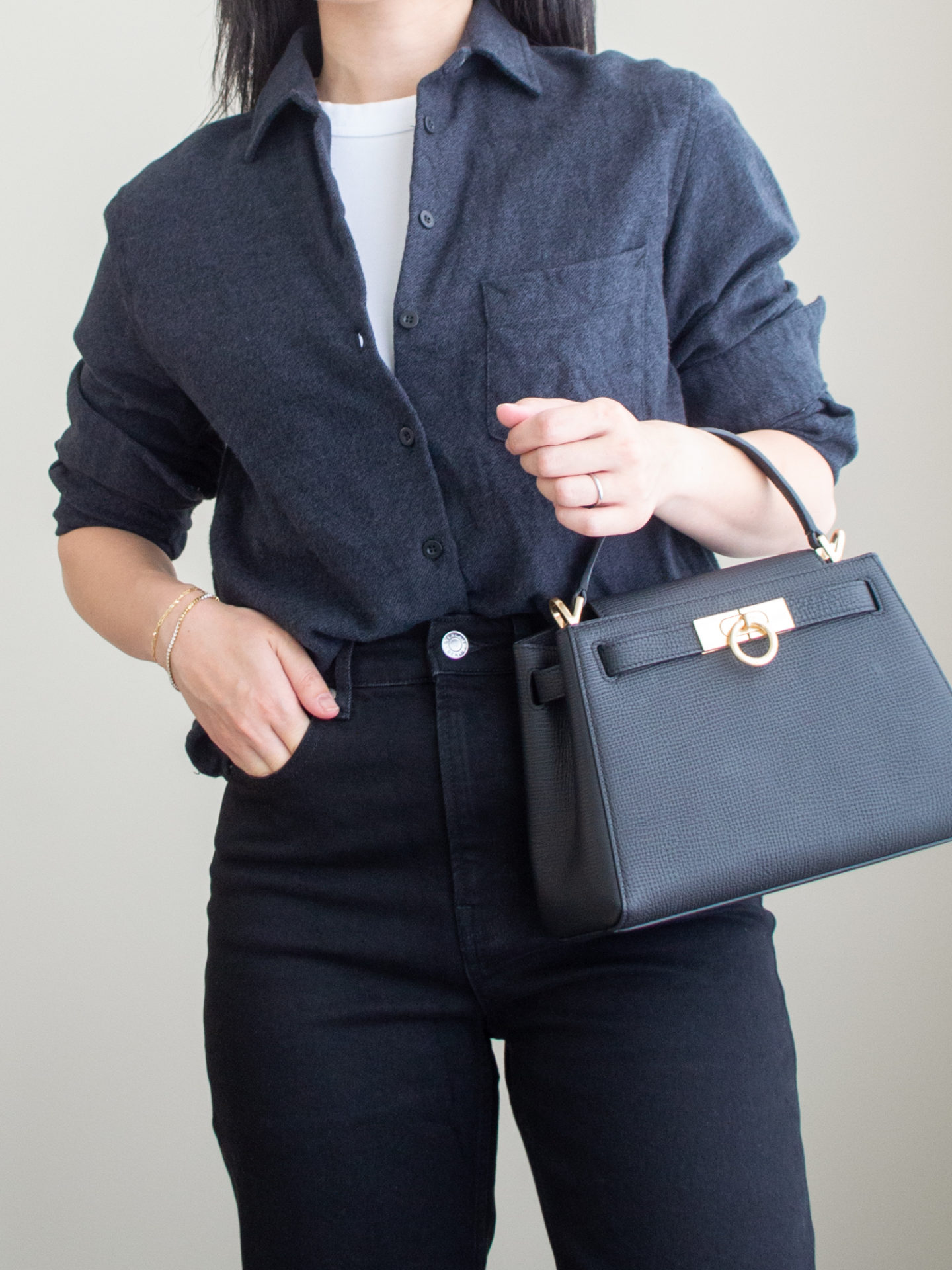 Close-up detailed outfit shot of Sharon of Her Simple Sole wearing a white T-shirt featuring a simple white T-shirta black button-up shirt, a pair of black straight leg jeans, and a black top handle | minimalist outfits | fall outfit ideas