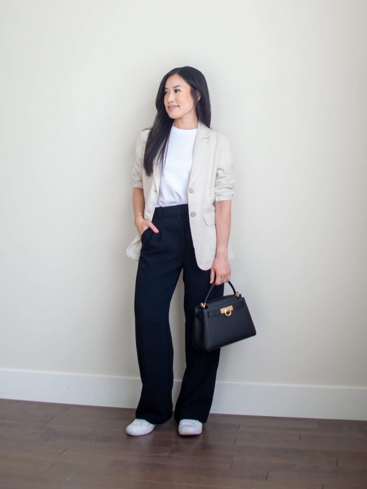 Sharon of Her Simple Sole is showcasing a t-shirt outfit for fall, featuring a simple white T-shirt, a cream linen blazer, a pair of black wide-leg pants, a black top handle bag and Converse monochrome white sneakers | minimalist outfits | fall outfit ideas