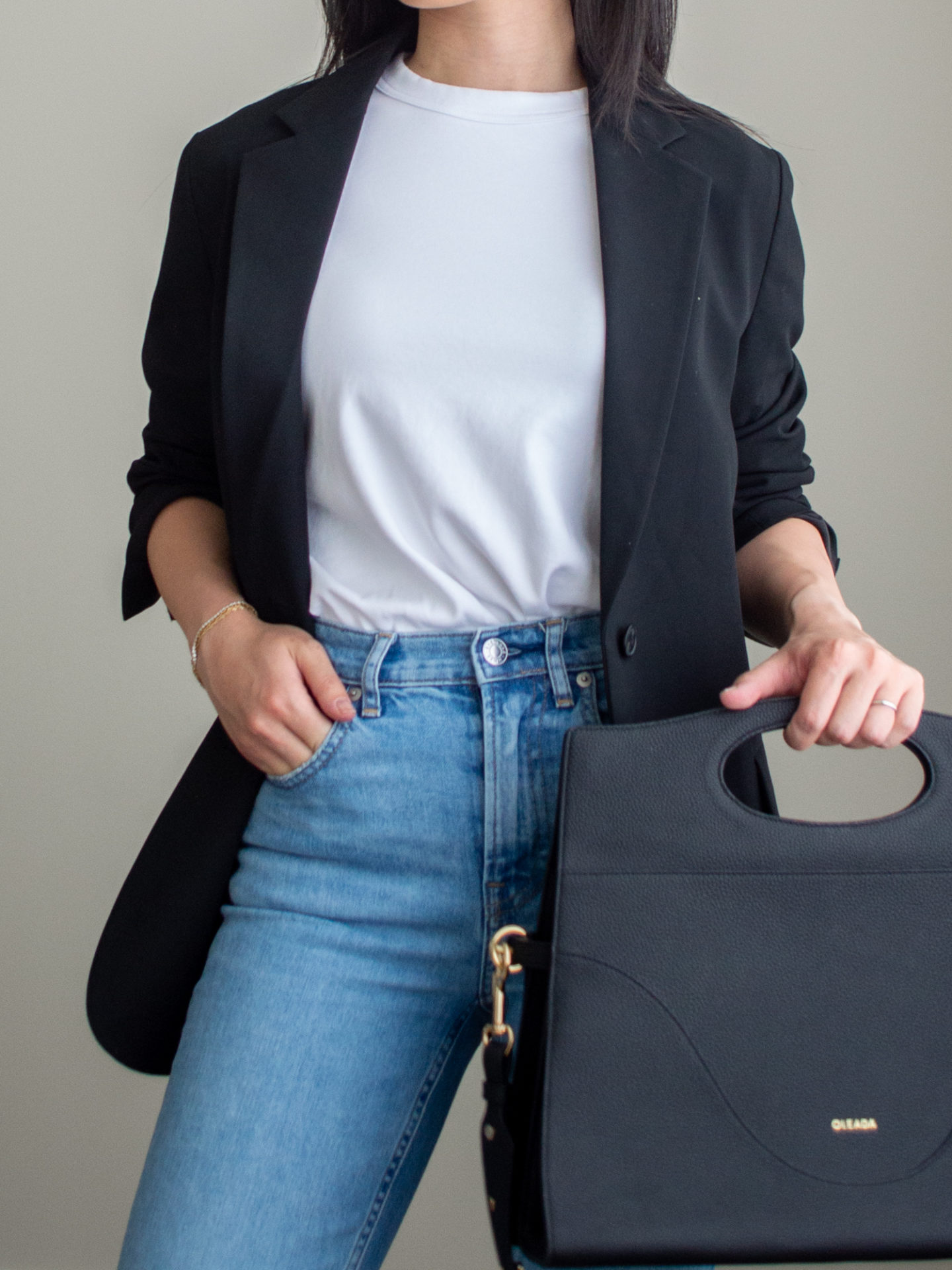 Close-up detailed outfit shot of Sharon of Her Simple Sole wearing a white T-shirt, a black blazer, blue straight fit jeans, and a black briefcase-style bag | minimalist outfits | fall outfit ideas