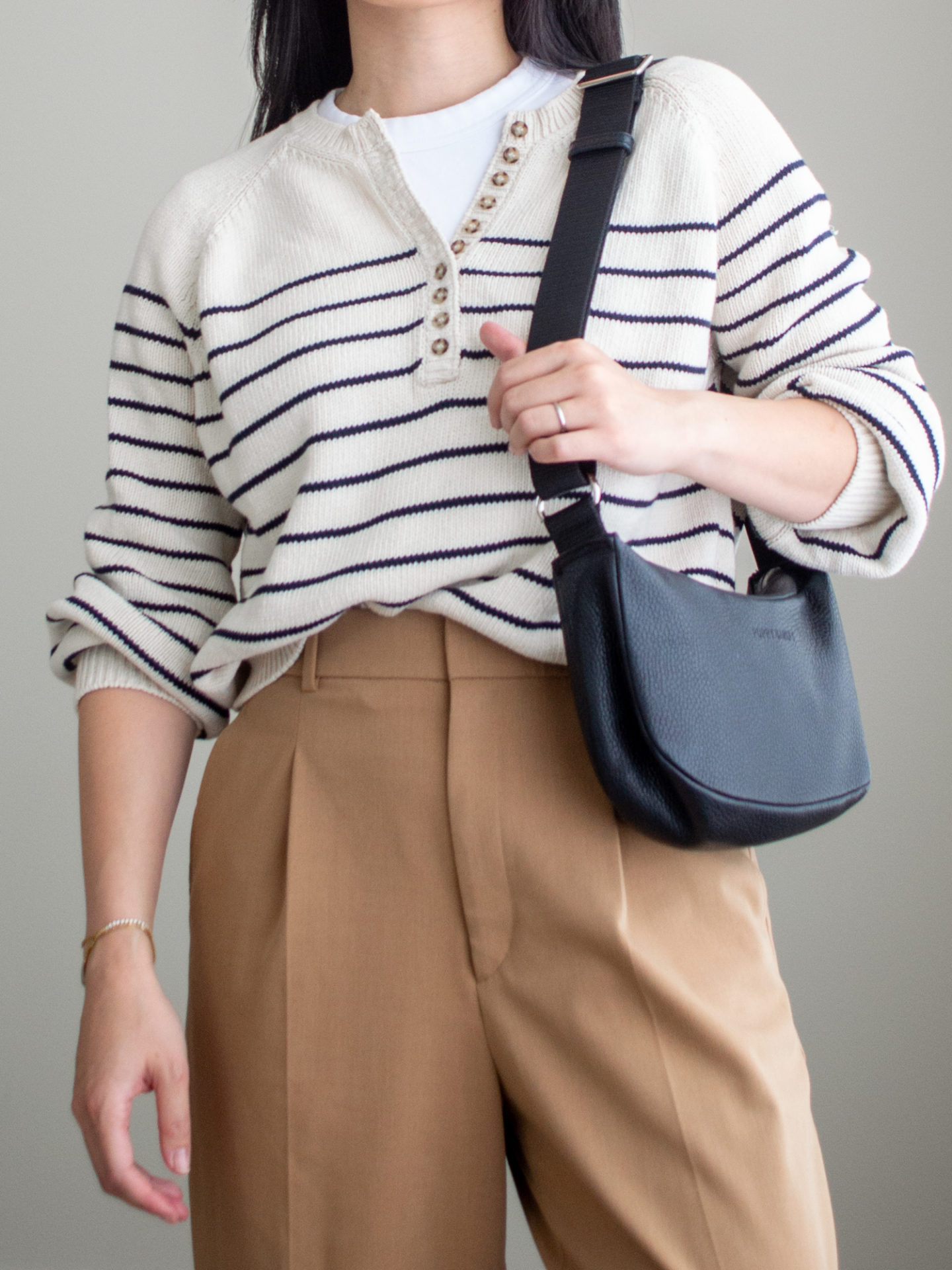 Close-up detailed outfit shot of Sharon of Her Simple Sole wearing a white T-shirt, a striped sweater, brown wide-leg pants, and a black slouchy bag | minimalist outfits | fall outfit ideas