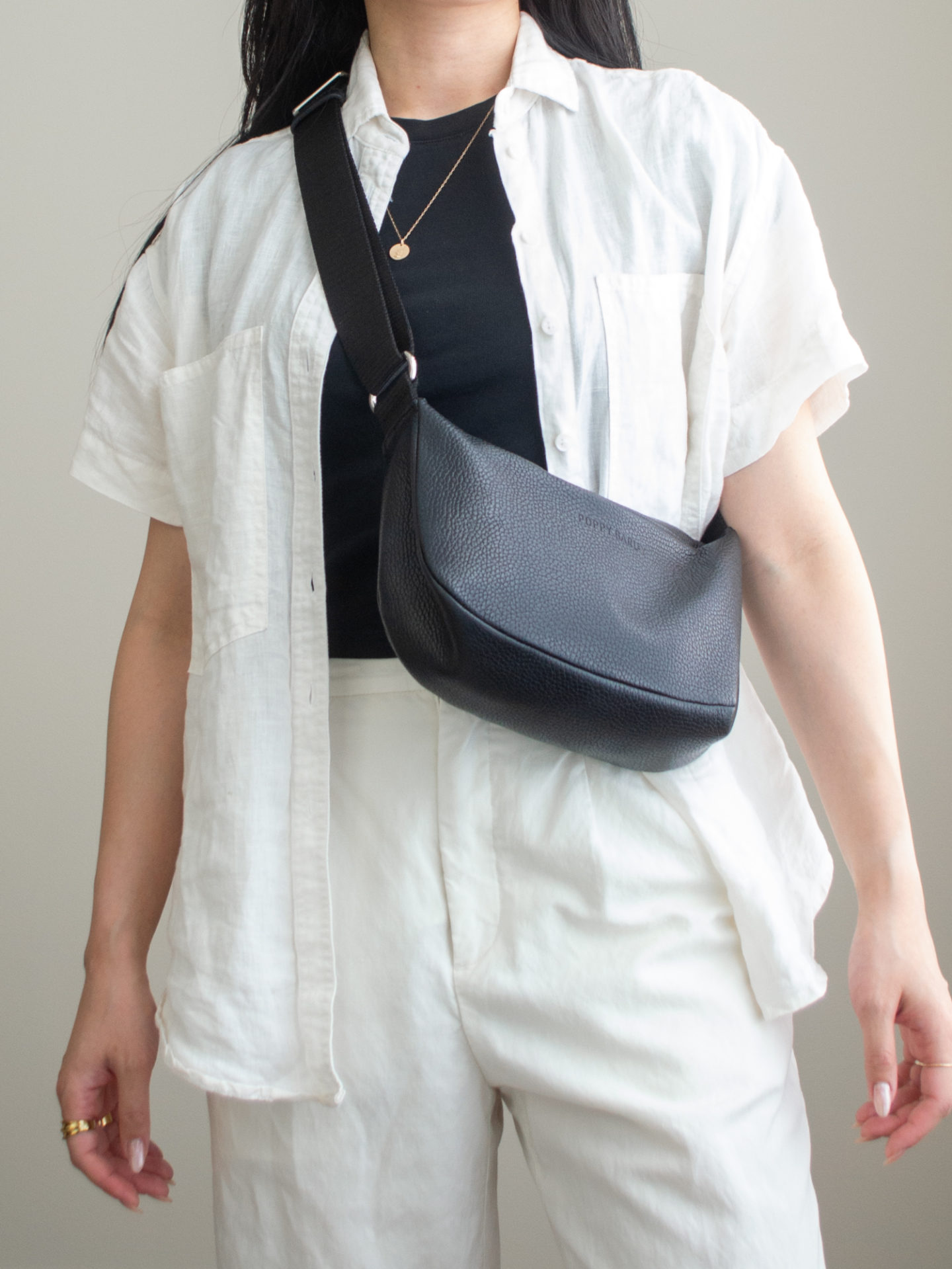 Close-up detailed outfit shot of Sharon of Her Simple Sole wearing a basic black T-shirt, a linen short sleeve button up shirt, cream wide leg linen pants, along with a black slouchy bag | minimalist outfits ideas | summer outfit ideas | linen outfit ideas