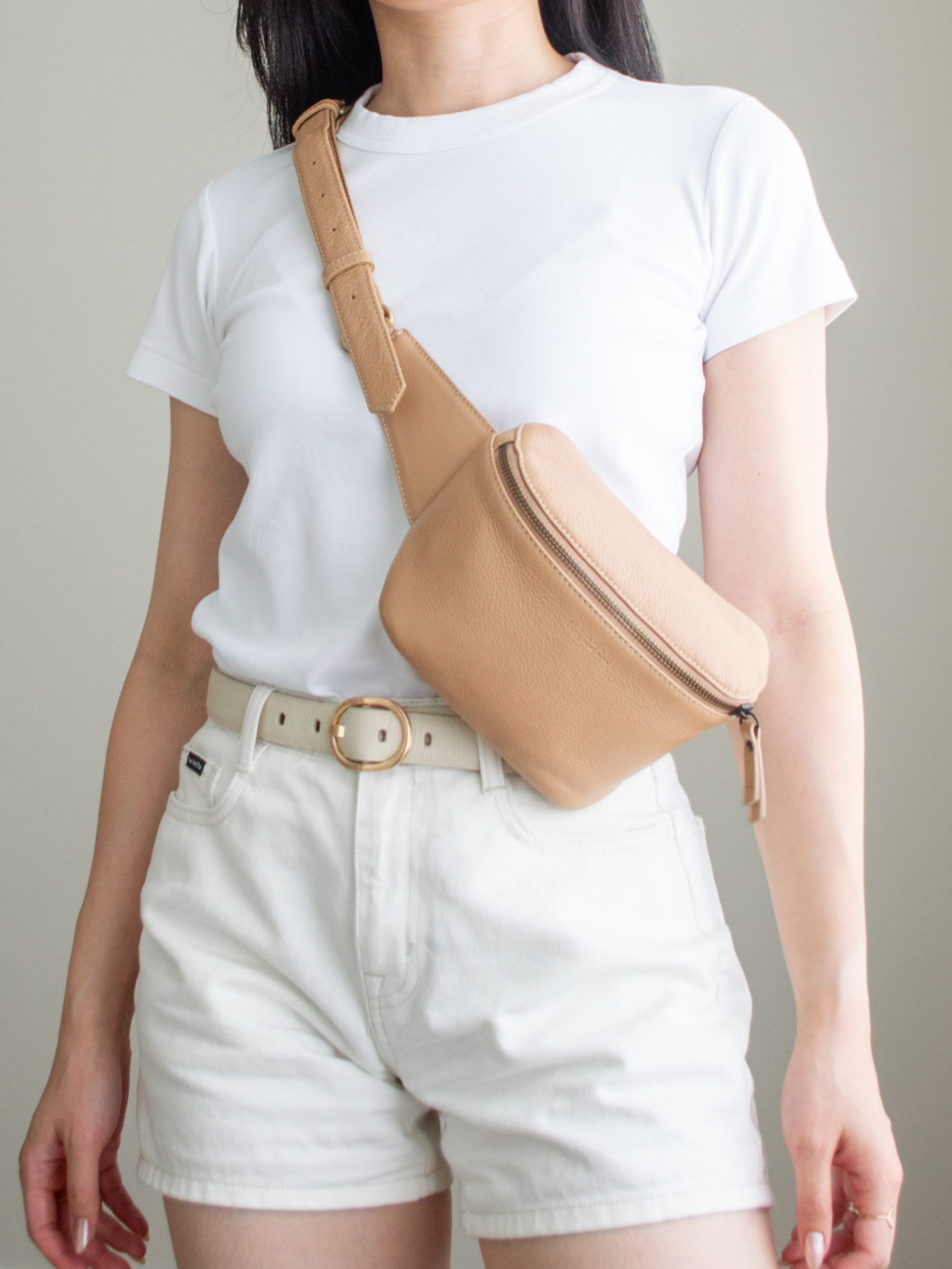 Close-up detailed outfit shot of Sharon of Her Simple Sole wearing a basic white T-shirt, white denim shorts, a cream belt and a tan belt bag | minimalist outfits ideas | summer outfit ideas