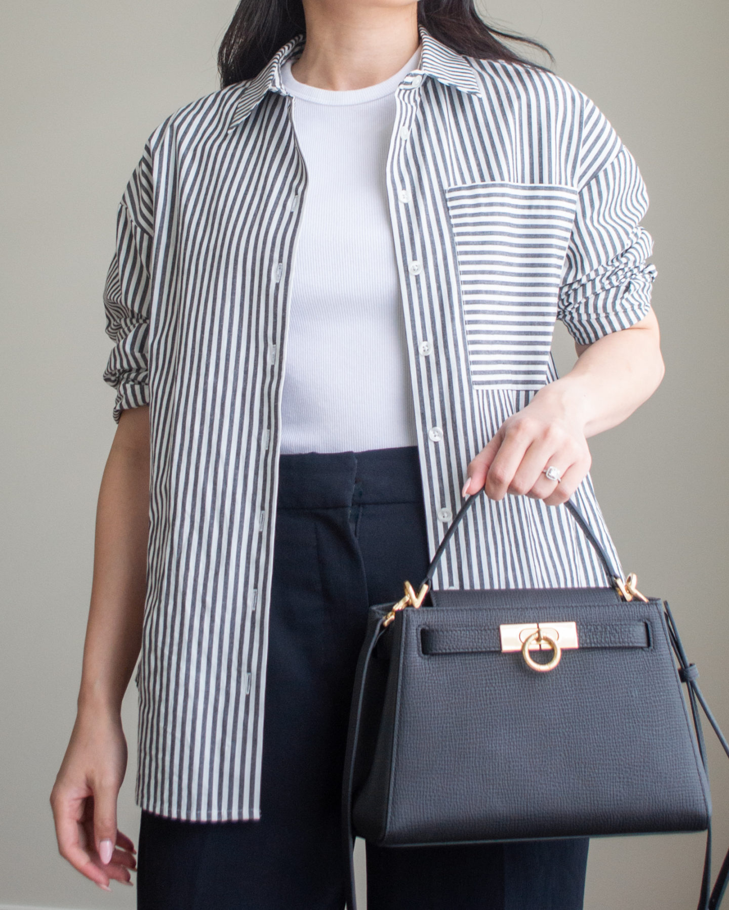 Close-up detailed outfit shot of Sharon of Her Simple Sole wearing a striped button up shirt, a basic white t-shirt, and black wide leg pants, while holding a black top handle bag | minimalist outfits | summer outfit ideas | smart casual outfit | wide leg pants outfit