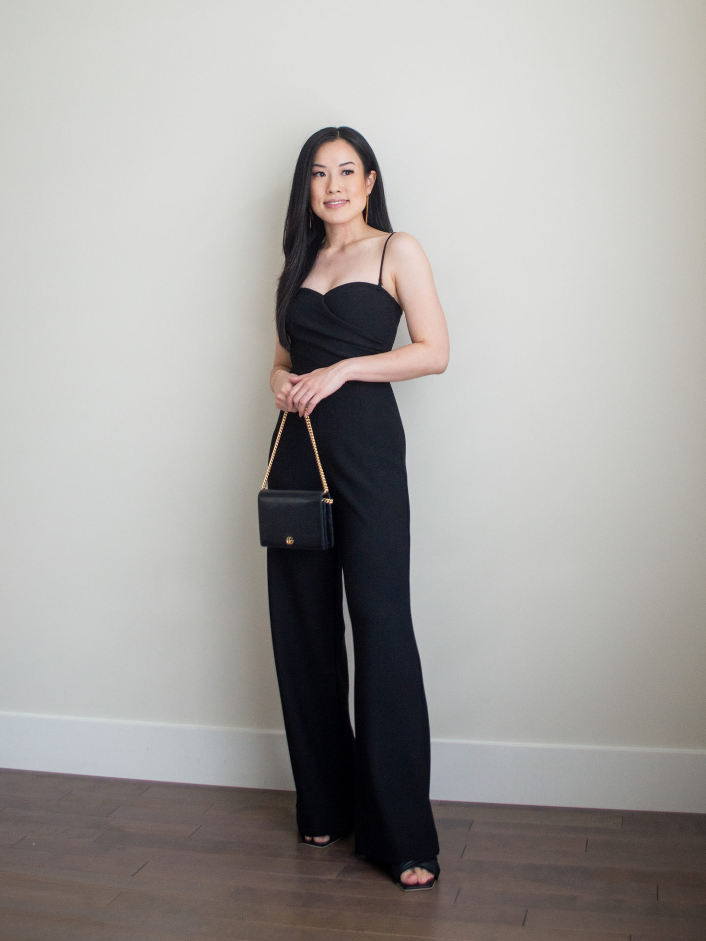 Sharon of Her Simple Sole is showcasing an outfits using simple pieces that make deciding what to pack easy, featuring a black jumpsuit while holding a black chain bag and heeled sandals | minimalist outfits | simple outfit ideas