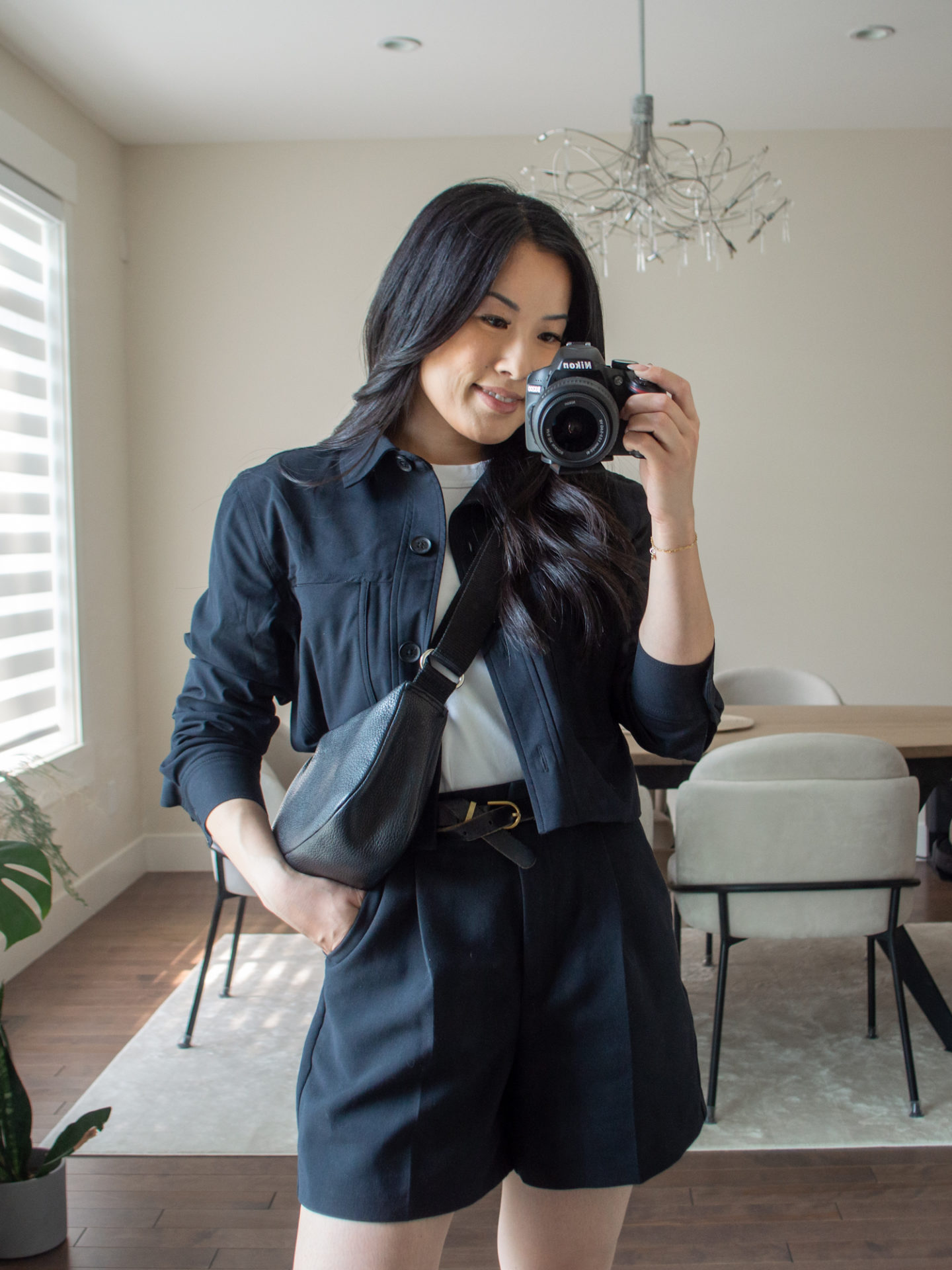 Close-up detailed outfit shot of Sharon of Her Simple Sole wearing a basic white T-Shirt, a black cropped jacket, black tailored shorts, and a black slouchy bag | minimalist outfits | simple outfit ideas