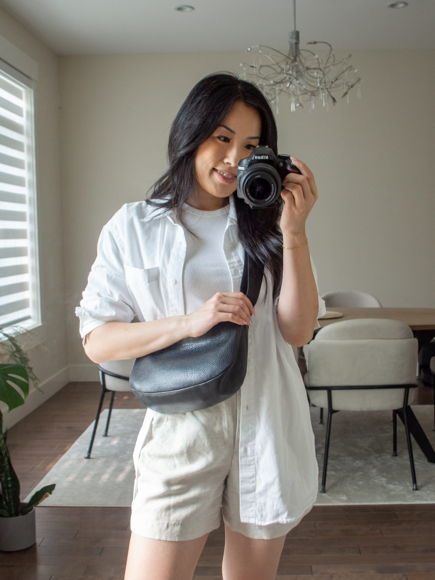 Close-up detailed outfit shot of Sharon of Her Simple Sole wearing a white baby T-Shirt, a white oversized button up shirt, cream linen shorts and a black slouchy bag | minimalist outfits | simple outfit ideas