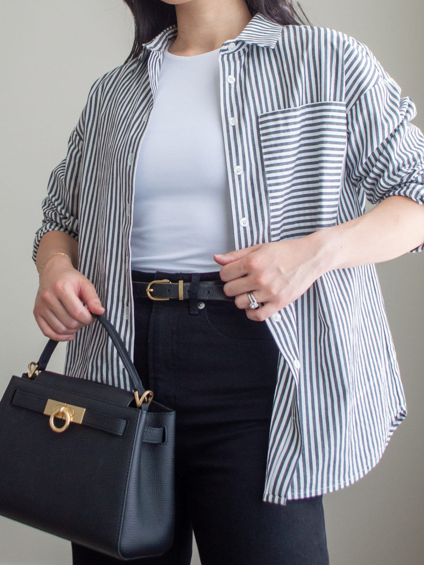 Close-up detailed outfit shot of Sharon of Her Simple Sole wearing a striped button up shirt, a baby t-shirt, black straight leg jeans and a black top handle bag | minimalist outfits | simple outfit ideas