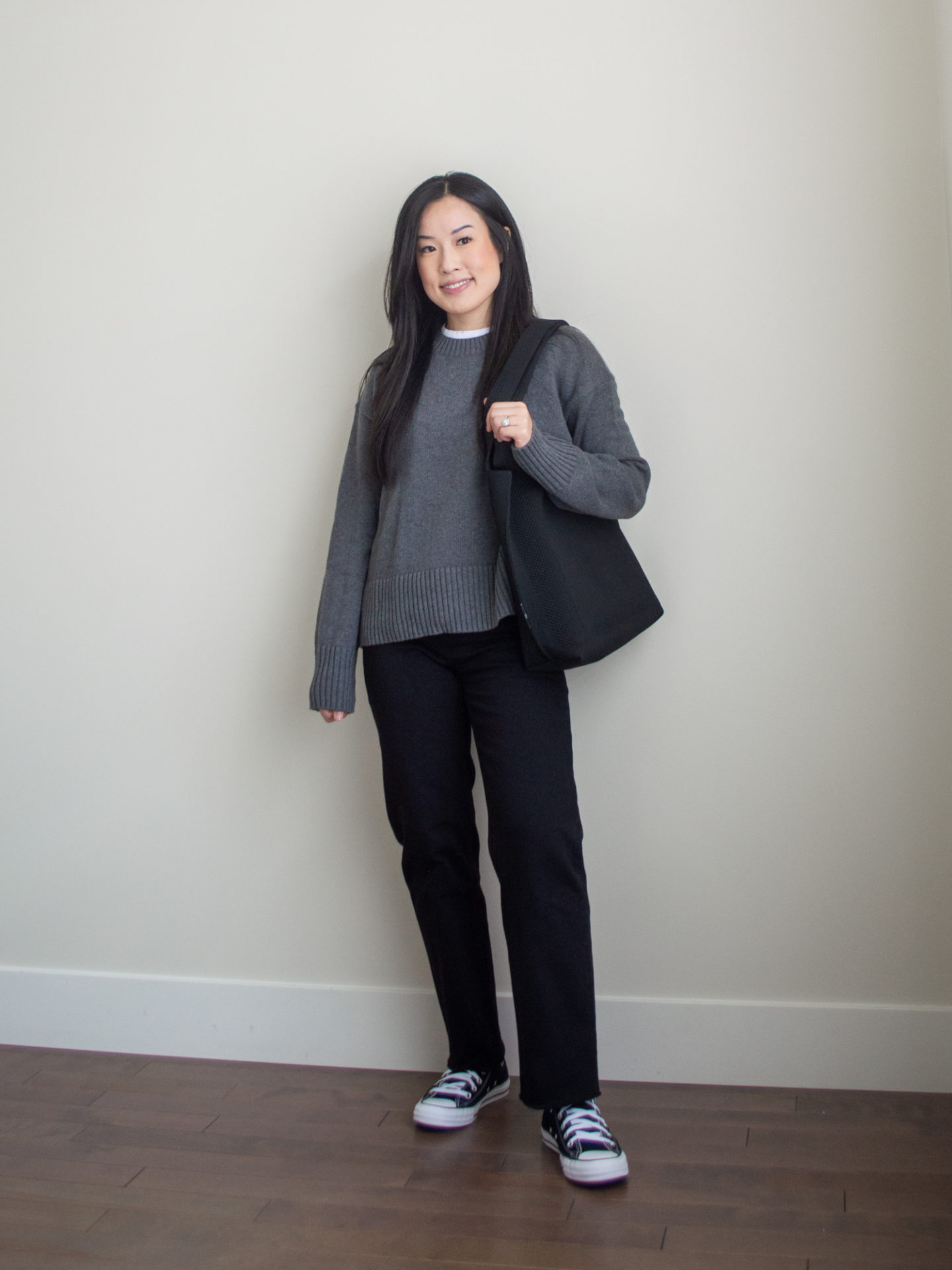 Sharon of Her Simple Sole is showcasing a outfit wearing one of her new Everlane staples, featuring a grey sweater, a white t-shirt, black straight leg jeans, a black tote bag and black Converse sneakers | minimalist outfits | simple outfit ideas