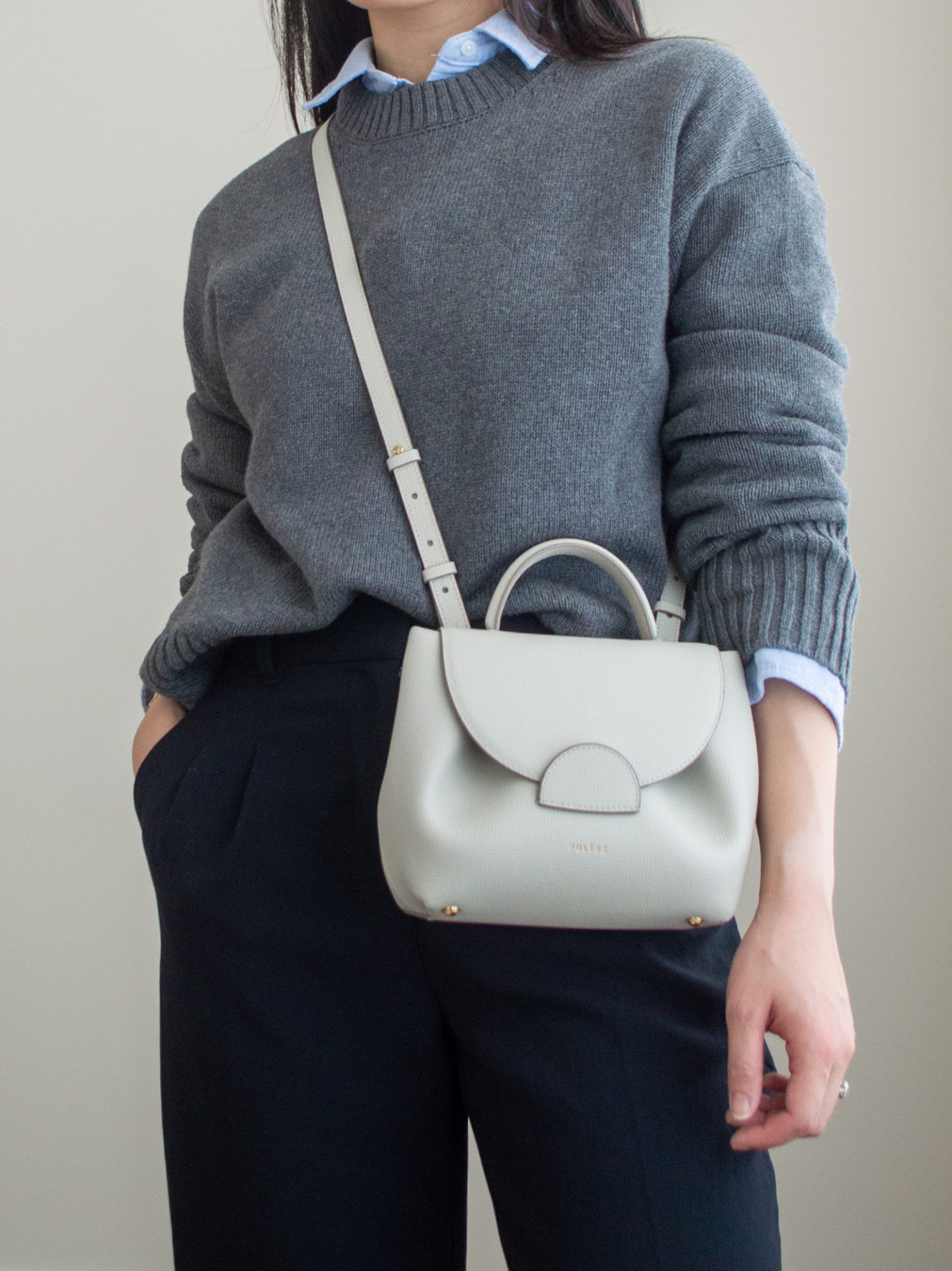 Close-up detailed outfit shot of Sharon of Her Simple Sole wearing a grey sweater, a blue relaxed button up shirt, black wide-leg pants and an off-white crossbody bag | minimalist outfits | simple outfit ideas