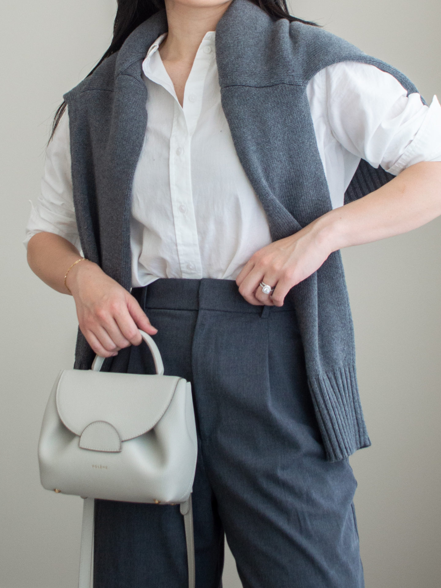 Close-up detailed outfit shot of Sharon of Her Simple Sole wearing a white linen button up shirt, a grey sweater, grey wide-leg pants and an off-white crossbody bag | minimalist outfits | simple outfit ideas