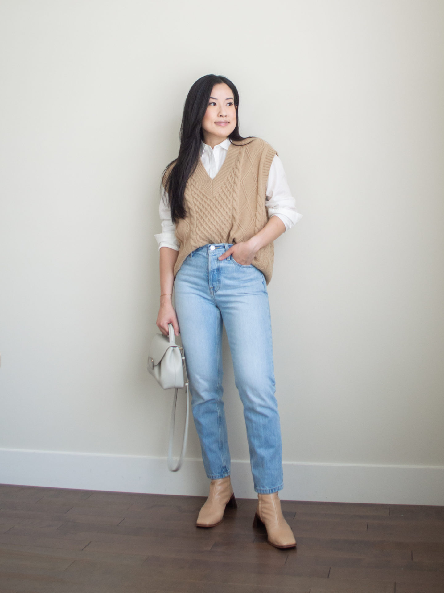 Sharon of Her Simple Sole is showcasing a outfit wearing one of her new Everlane staples, featuring a white button up shirt, a brown sweater vest, blue straight-leg jeans, an off-white crossbody bag and nude ankle boots | minimalist outfits | simple outfit ideas