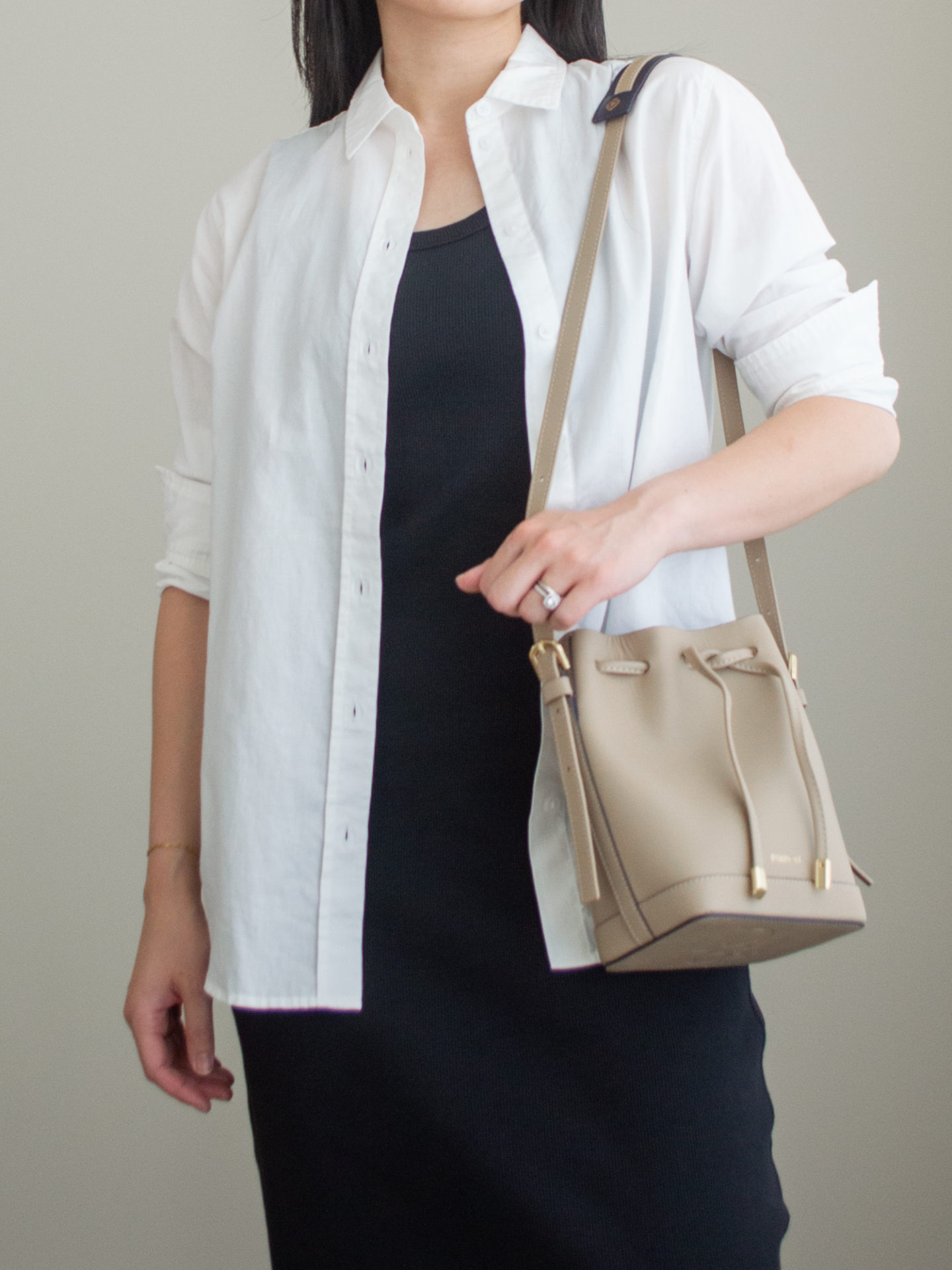 Close-up detailed outfit shot of Sharon of Her Simple Sole wearing a black midi dress, a white button up shirt and a taupe bucket bag | minimalist outfits | simple outfit ideas