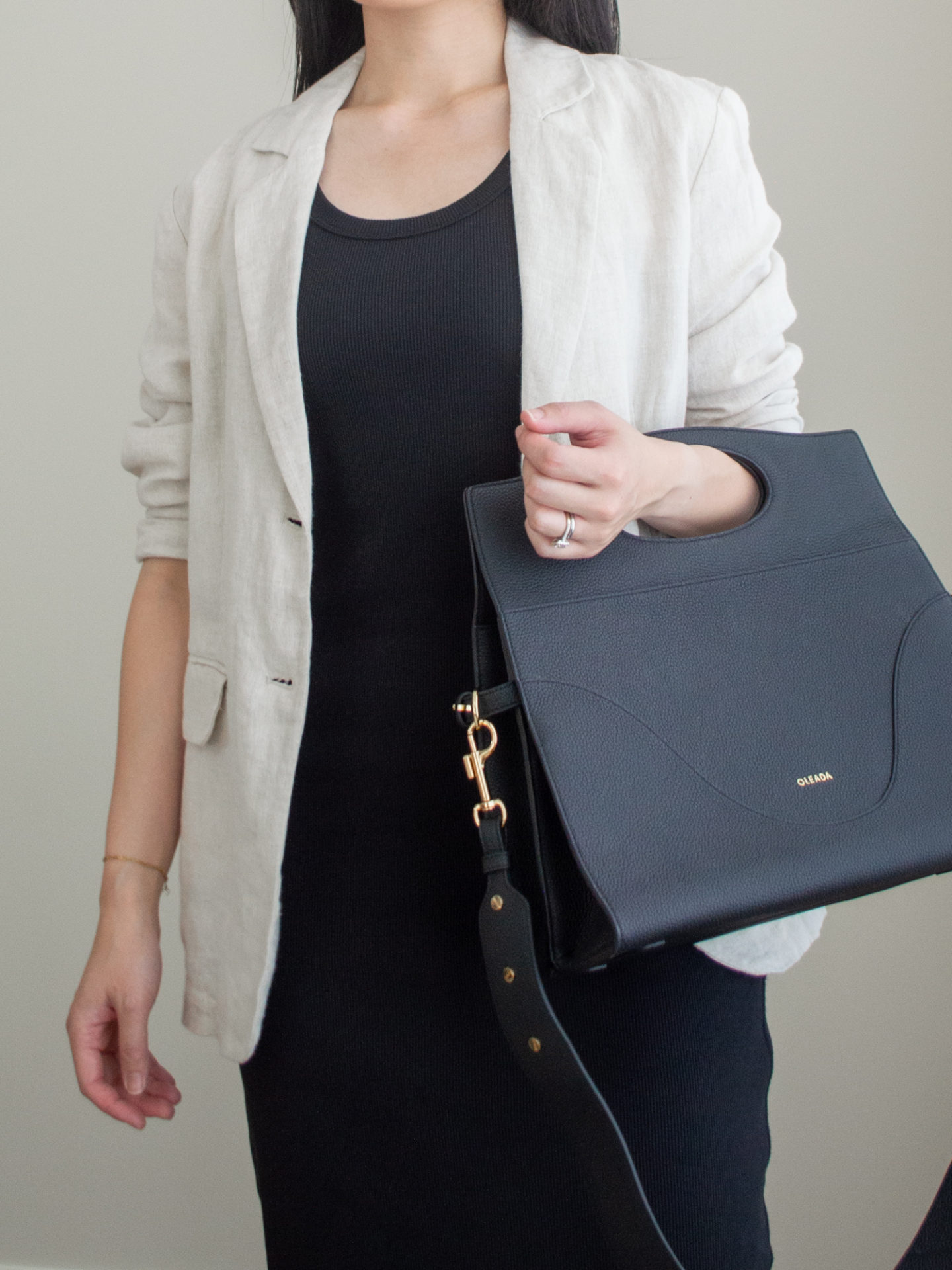 Close-up detailed outfit shot of Sharon of Her Simple Sole wearing a black midi dress, a linen blazer and a black briefcase style bag | minimalist outfits | simple outfit ideas