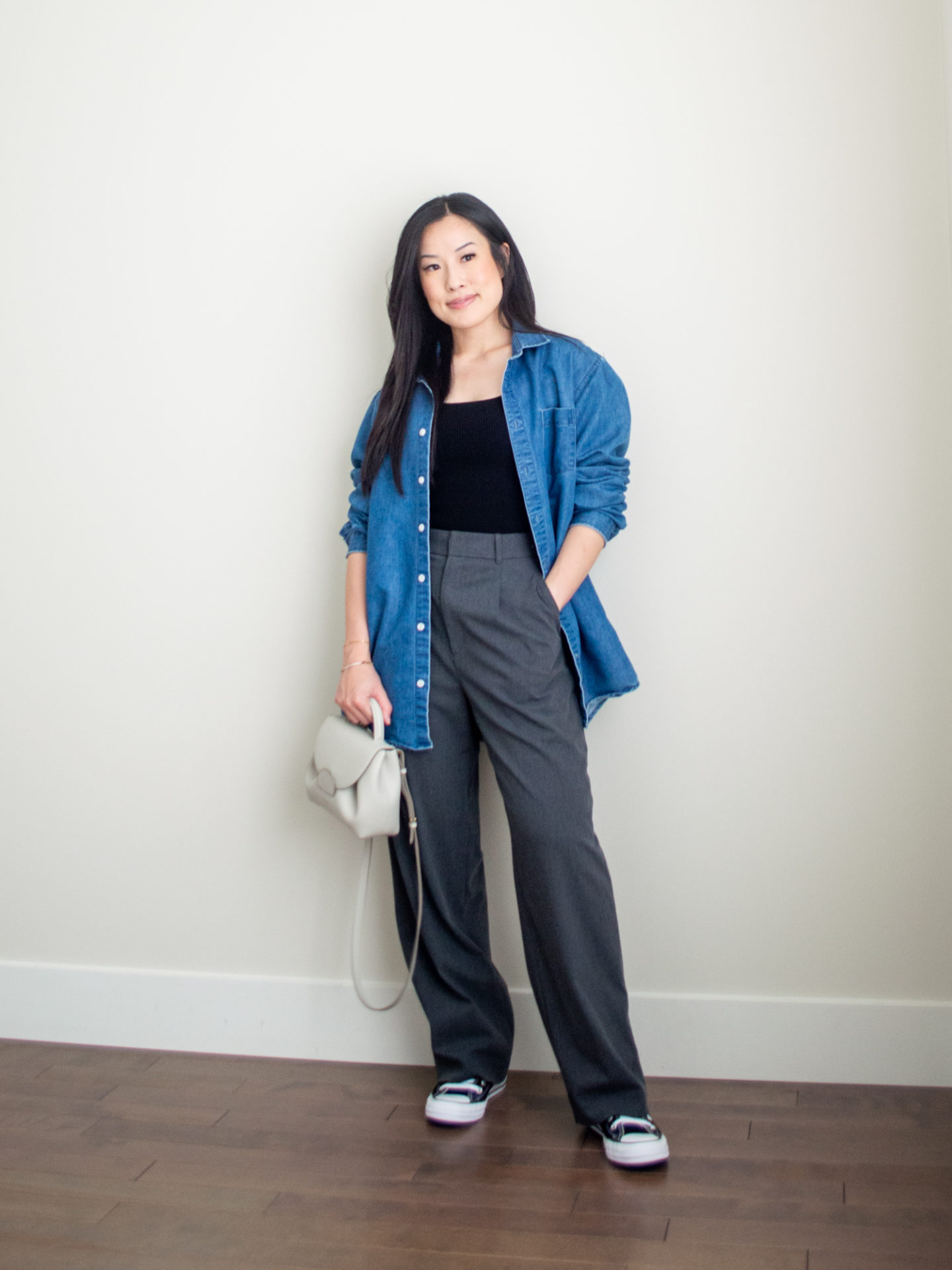 Sharon of Her Simple Sole is showcasing a outfit from her August outfit roundup, featuring black square neck tank top, an oversized denim shirt, grey wide-leg pants, and an off-white crossbody bag and a pair of black Converse Chuck Taylor All Star sneakers | minimalist outfits | simple outfit ideas