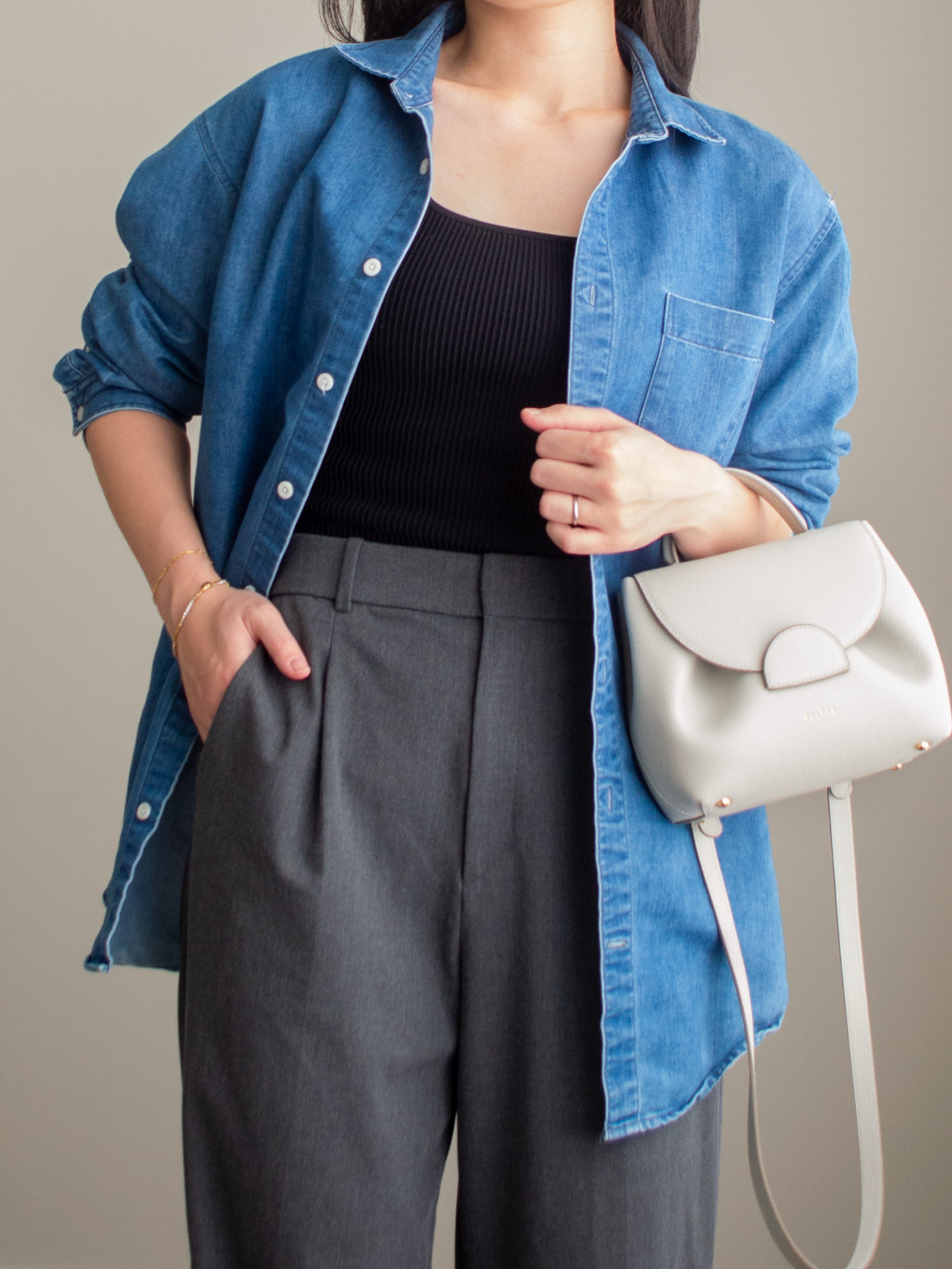 Close-up detailed outfit shot of Sharon of Her Simple Sole wearing a black square neck tank top, an oversized denim shirt, grey wide-leg pants, and an off-white crossbody bag | minimalist outfits | simple outfit ideas