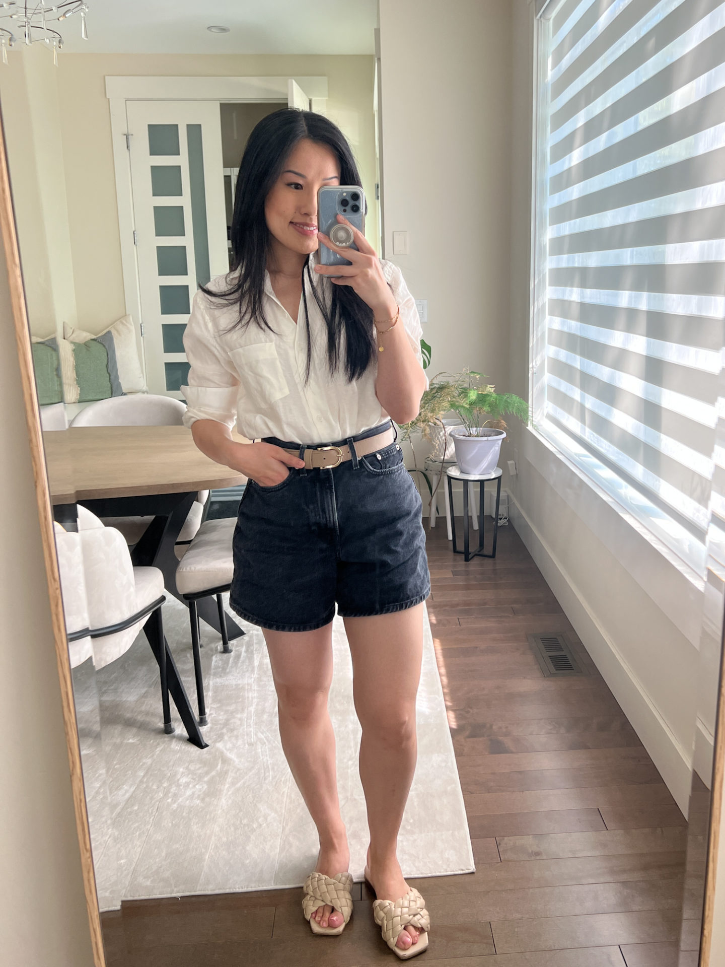 Sharon of Her Simple Sole is showcasing a outfit from her August outfit roundup, featuring an oversized white button-up shirt, black denim shorts, a nude belt and a pair of criss-cross sandals | minimalist outfits | simple outfit ideas