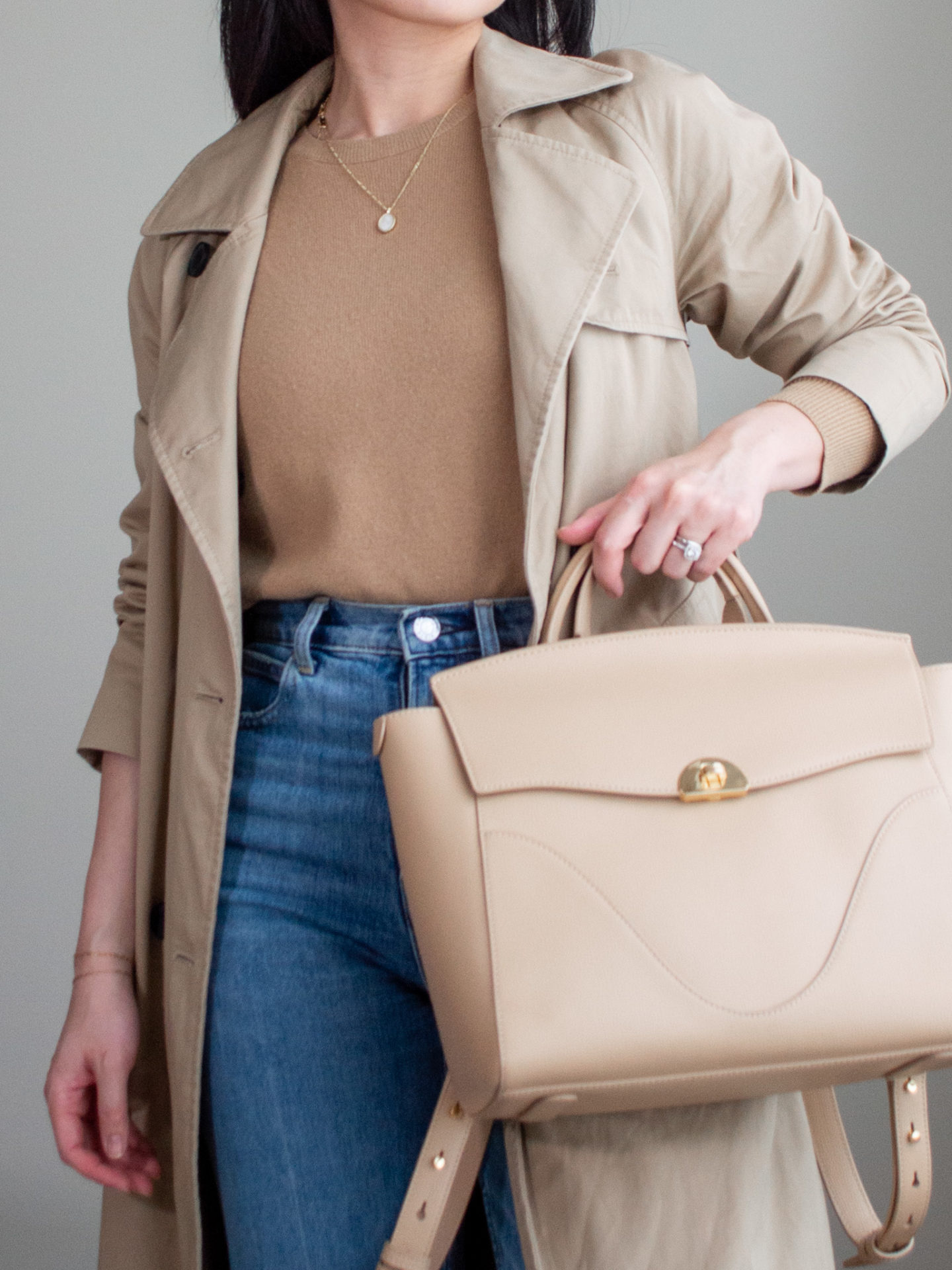 Close-up detailed outfit shot of Sharon of Her Simple Sole wearing a light brown cashmere sweater, brown trench coat, blue straight leg jeans and a cream workwear backpack | minimalist outfits | fall outfit ideas | simple outfit ideas