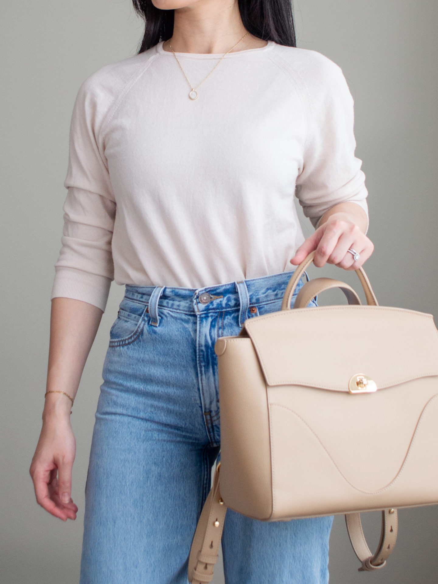 Close-up detailed outfit shot of Sharon of Her Simple Sole wearing a cream merino wool sweater, blue straight-fit jeans, tan workwear backpack | minimalist outfits | fall outfit ideas | simple outfit ideas