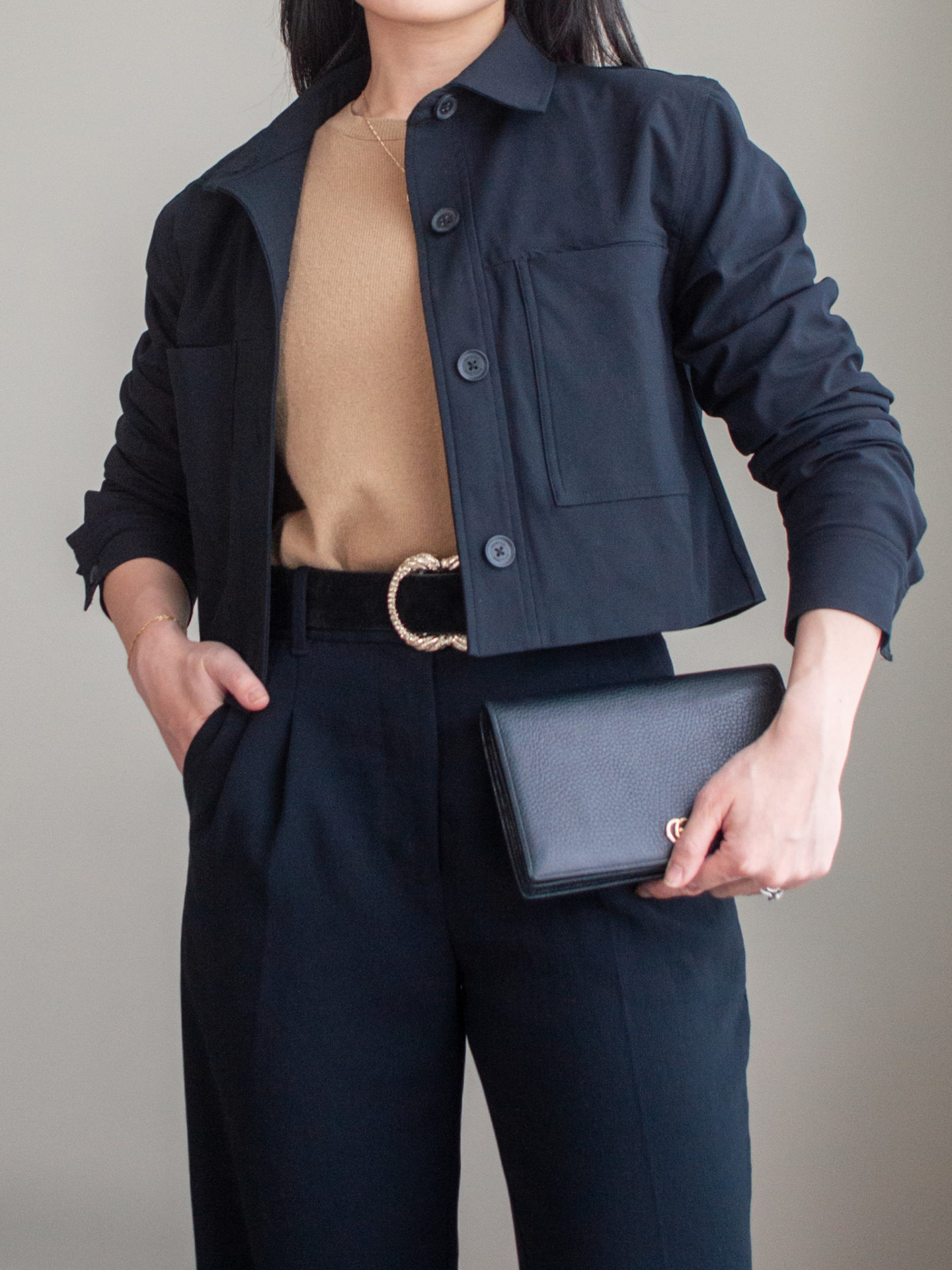 Close-up detailed outfit shot of Sharon of Her Simple Sole wearing a light brown cashmere sweater, black cropped jacket, black wide-leg pants, black statement belt, and a black wallet chain bag | minimalist outfits | fall outfit ideas | simple outfit ideas