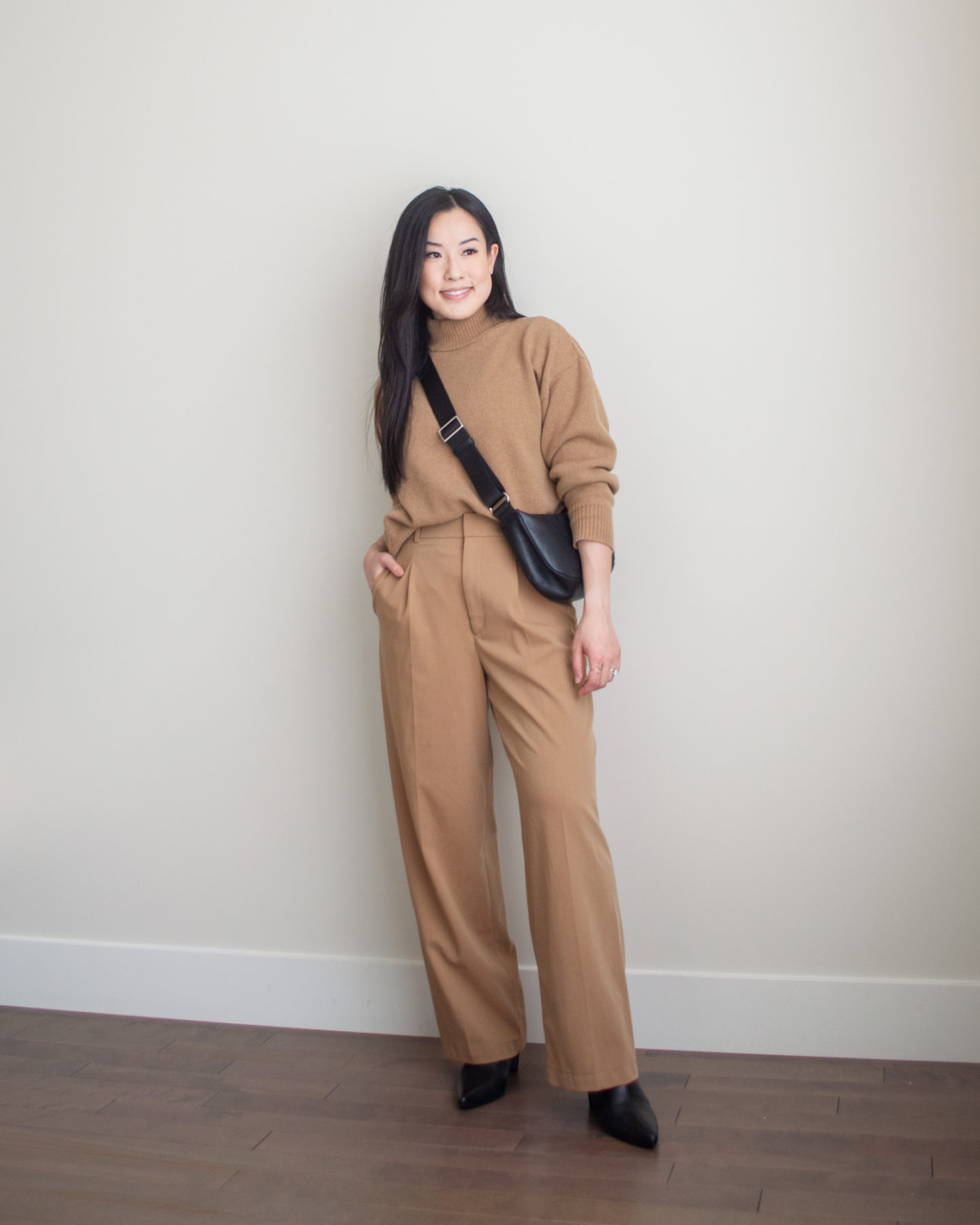 Sharon of Her Simple Sole is showcasing an outfit from her September outfit roundup, featuring a brown mockneck sweater, brown wide-leg pants, a black slouchy bag and black pointed toe ankle boots | minimalist outfits | simple outfit ideas