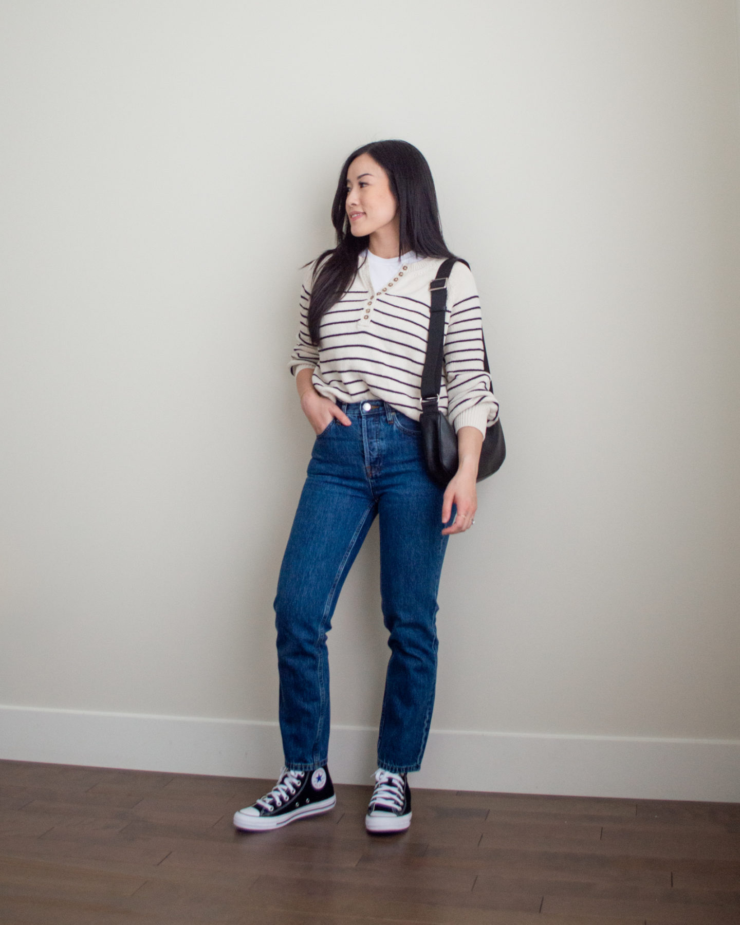 Sharon of Her Simple Sole is showcasing an outfit from her September outfit roundup, featuring a basic white T-Shirt, a striped cotton sweater, dark blue straight leg jeans, a black slouchy bag and black Converse sneakers | minimalist outfits | simple outfit ideas