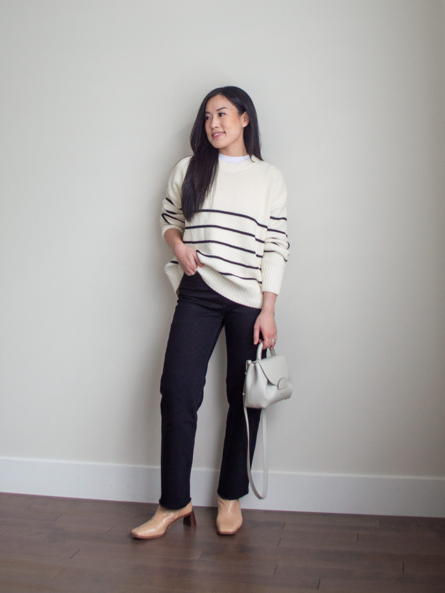 Sharon of Her Simple Sole is showcasing an outfit from her September outfit roundup, featuring a basic white T-Shirt, a striped cotton sweater, black straight leg jeans, an off-white crossbody bag and nude ankle boots | minimalist outfits | simple outfit ideas