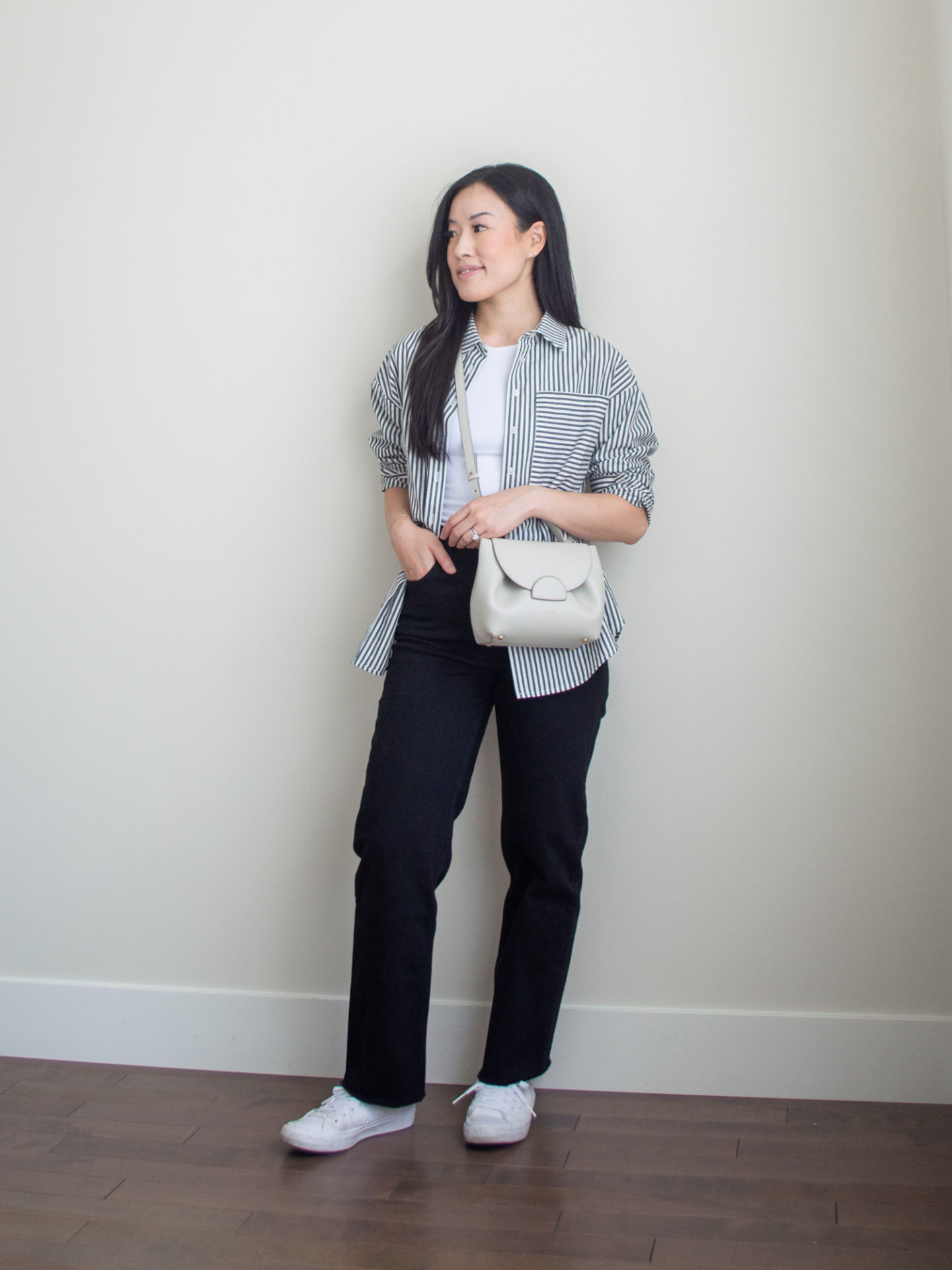 Sharon of Her Simple Sole is showcasing an outfit from her September outfit roundup, featuring a basic white bodysuit, a striped button up shirt, black straight leg jeans, an off-white crossbody bag and white sneakers | minimalist outfits | simple outfit ideas