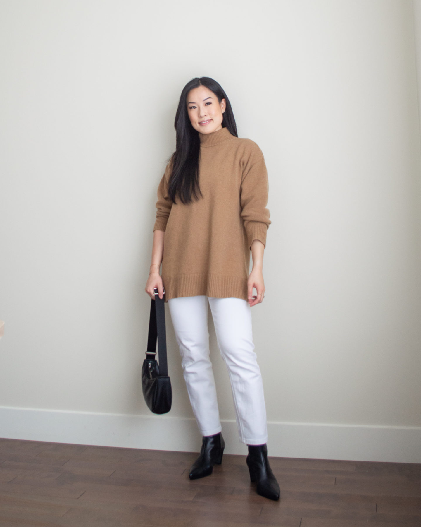 Sharon of Her Simple Sole is showcasing an outfit from her September outfit roundup, featuring a brown mockneck sweater, white straight leg jeans, a black slouchy bag and black pointed toe ankle boots | minimalist outfits | simple outfit ideas