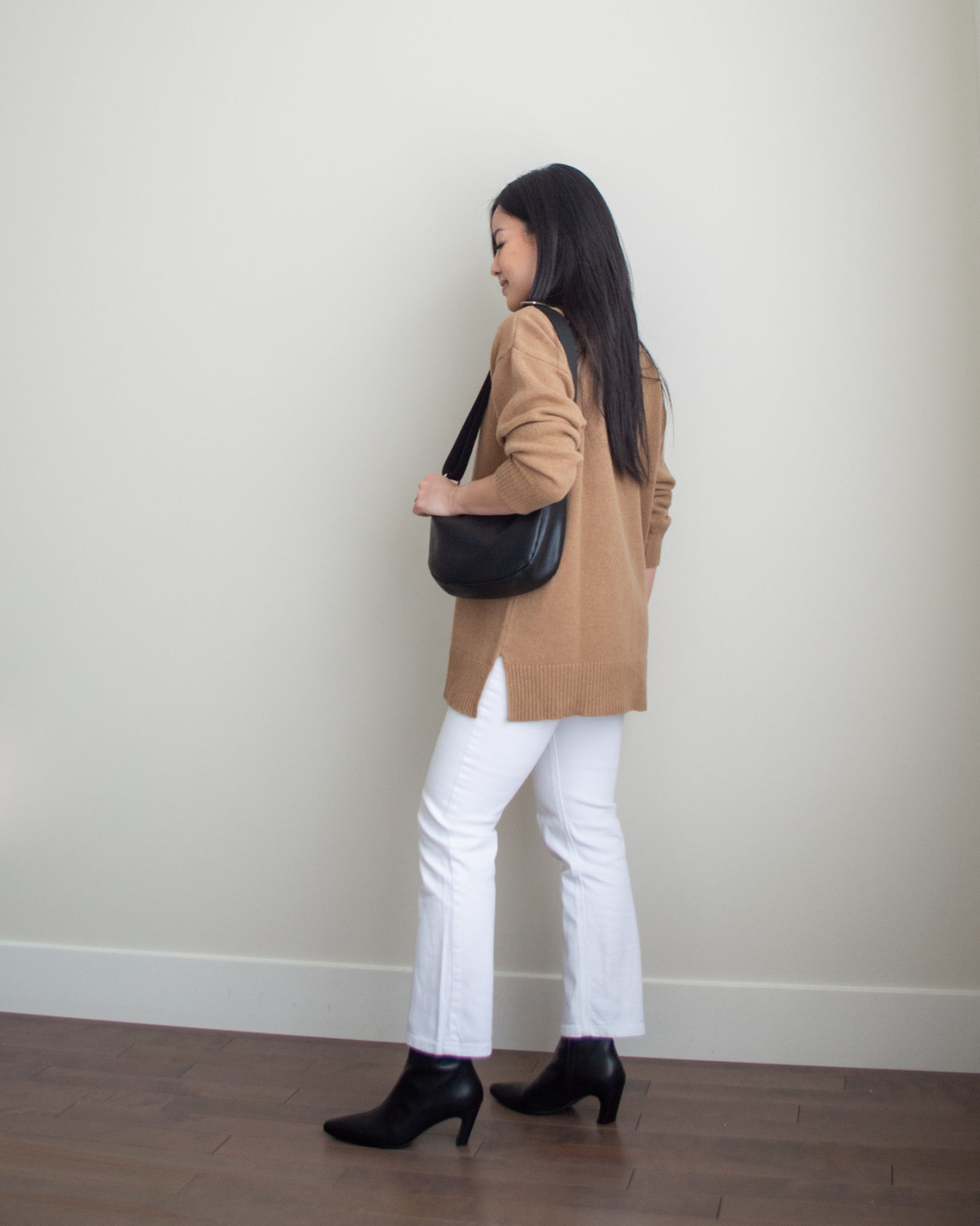 Sharon of Her Simple Sole is showcasing an outfit from her September outfit roundup, featuring a brown mockneck sweater, white straight leg jeans, a black slouchy bag and black pointed toe ankle boots | minimalist outfits | simple outfit ideas